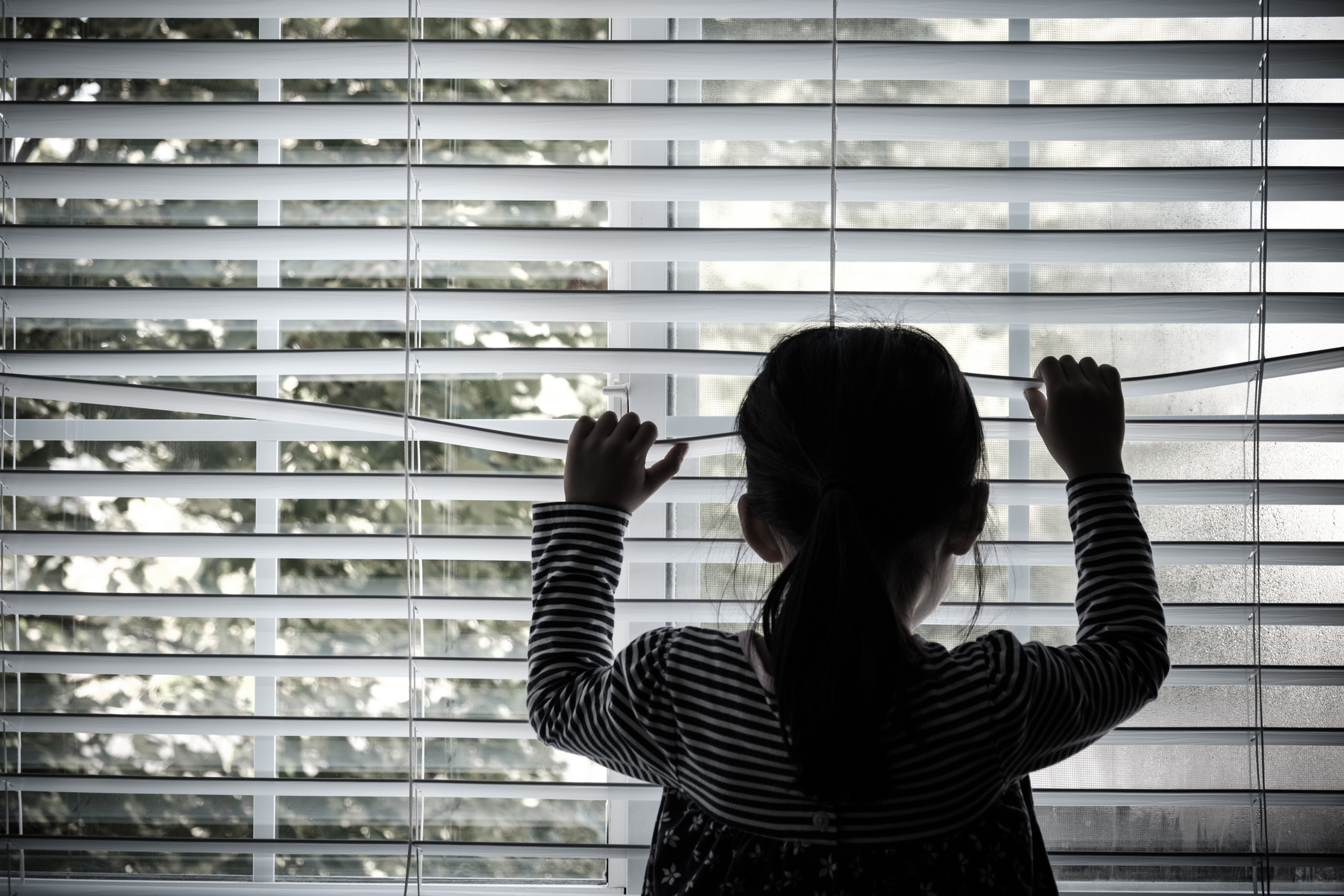 Lonely little kid in front of a window