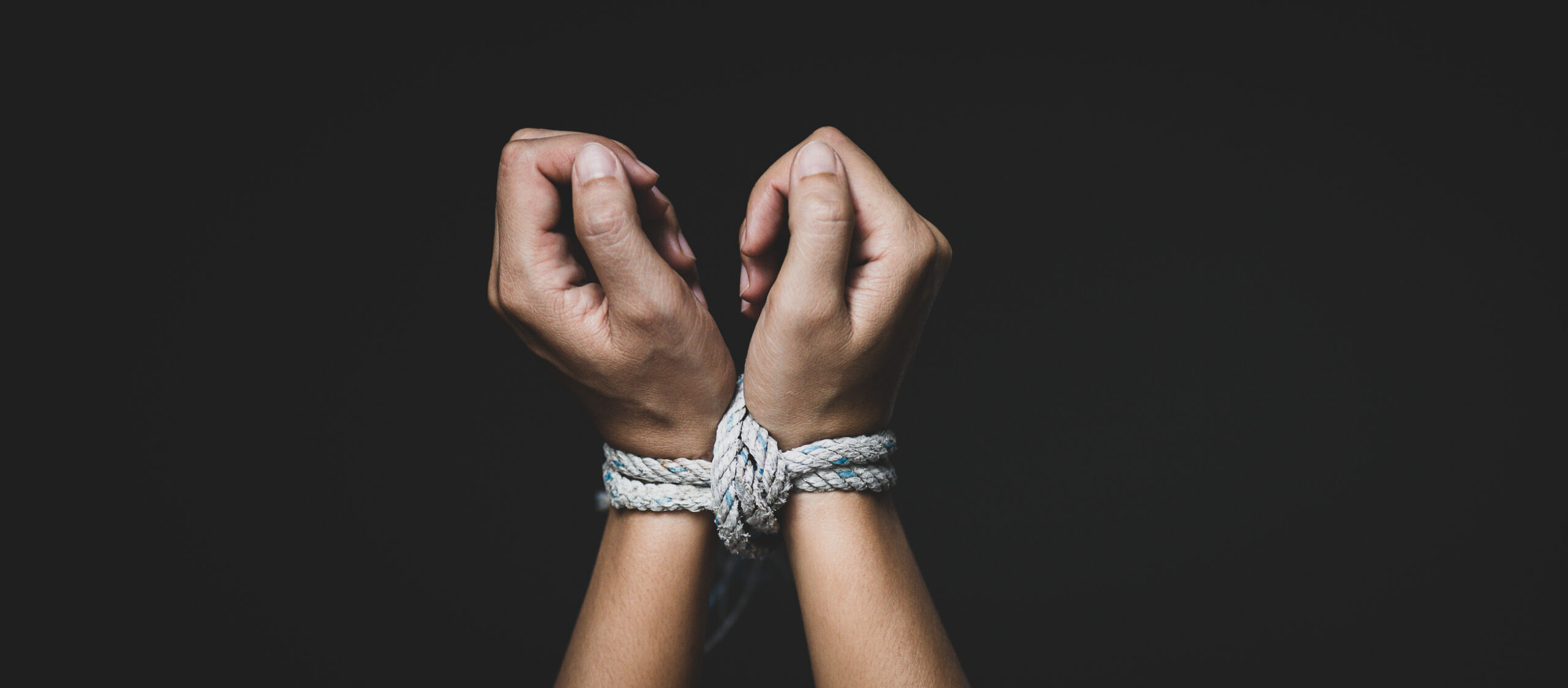 Woman hand tied up with rope, depicting the idea of freedom of the press or freedom of expression on dark background in low key. International human right day concept.