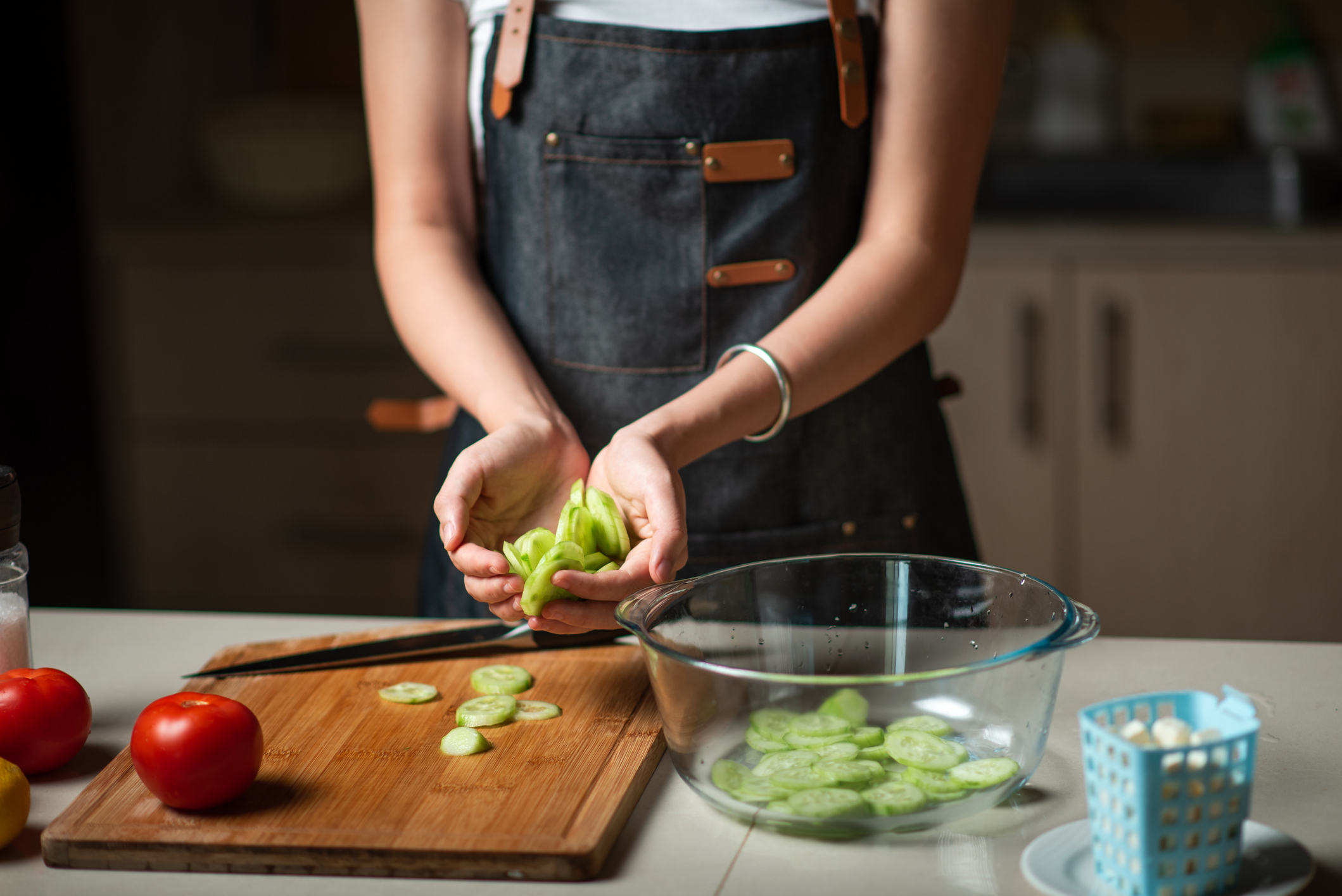 Woman making cucumber tomato vegetable salad at home