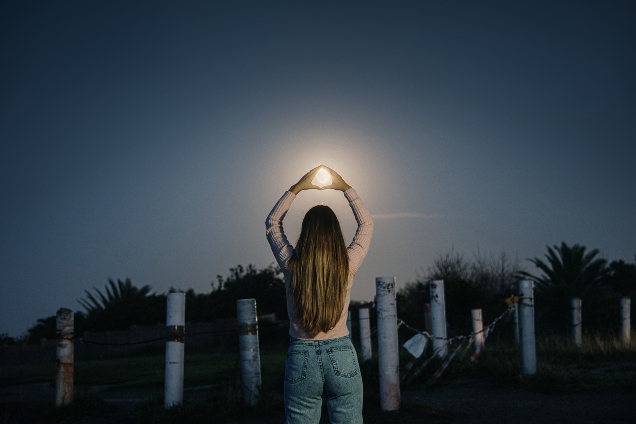 Rear view of young woman holding the Moon