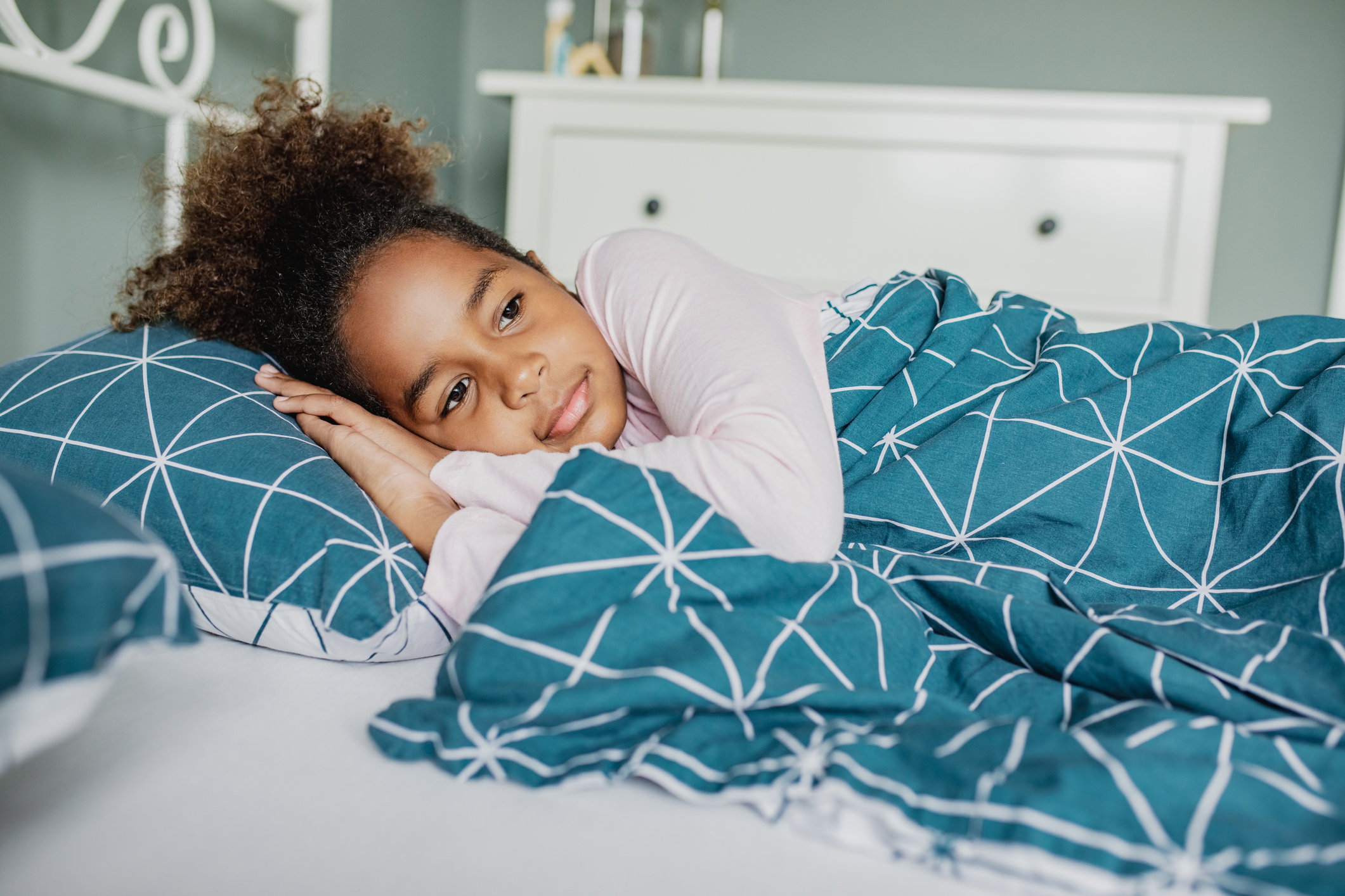 A little worried girl is waking up in bed