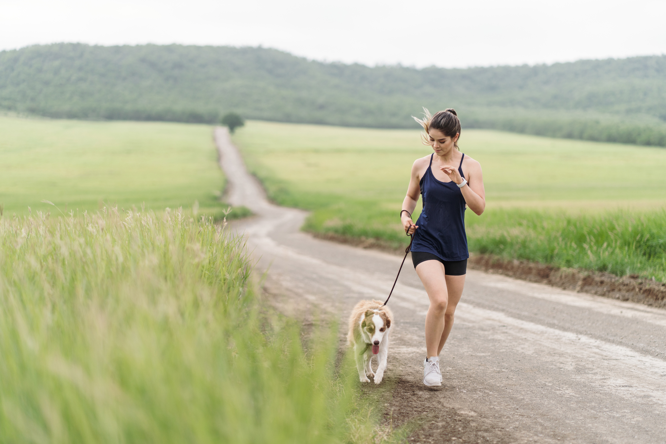 Cute young woman and dog walking outside