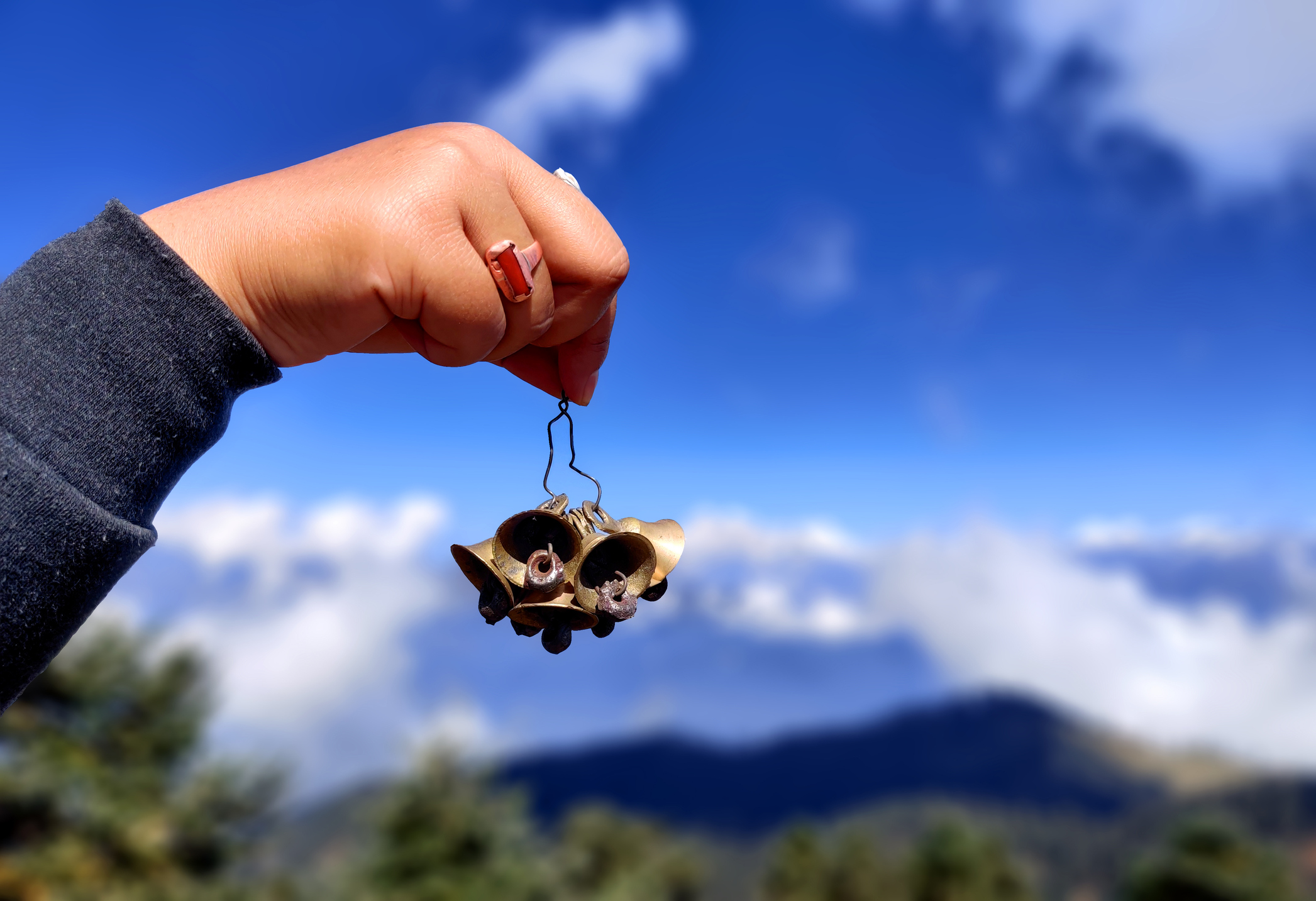 hand holding bunch of bells against blue sky. girl holding the temple bells.