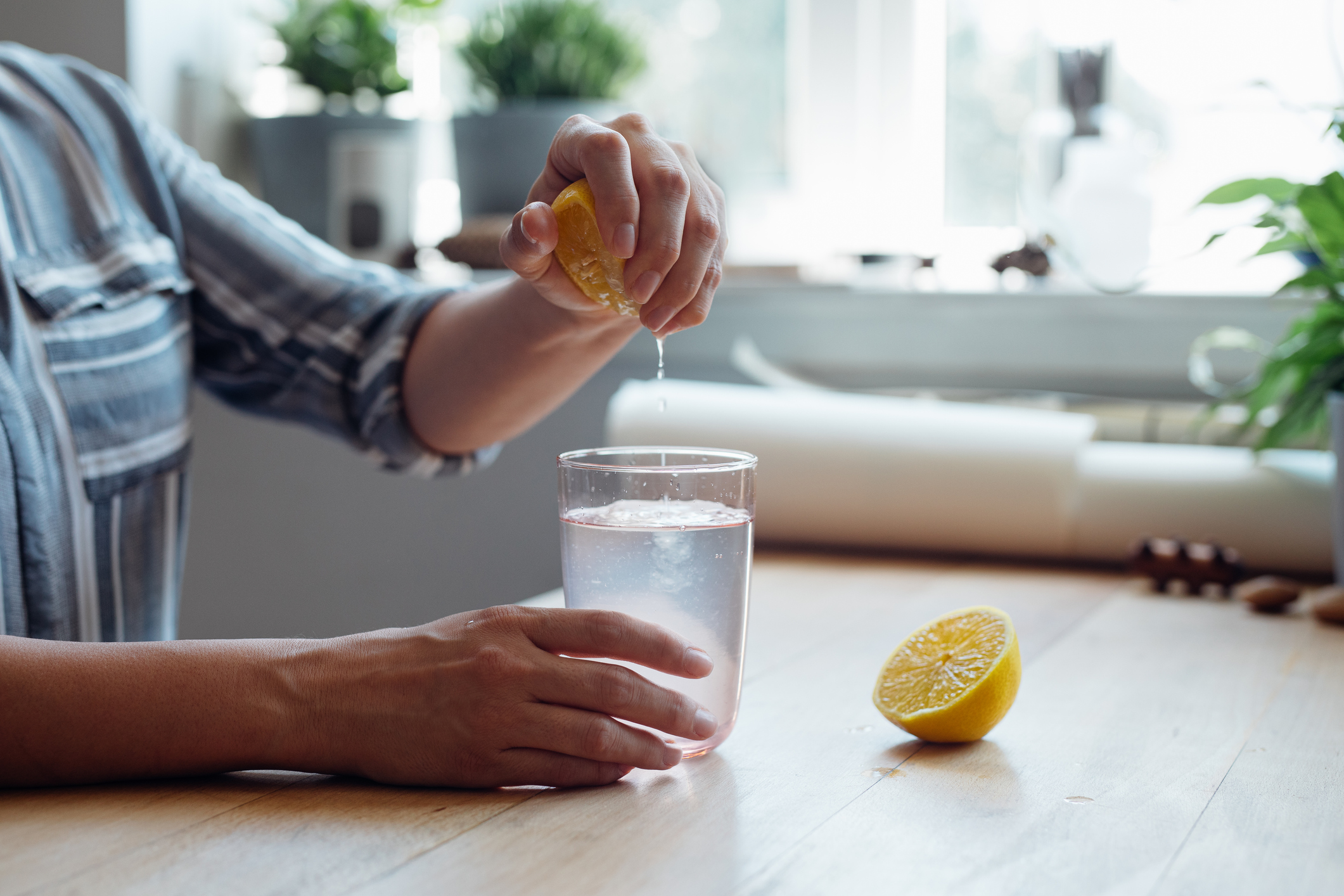 Close up Shot of an Anonymous Young Woman Squeezing a Lemon into a Cup of Water Making Lemonade