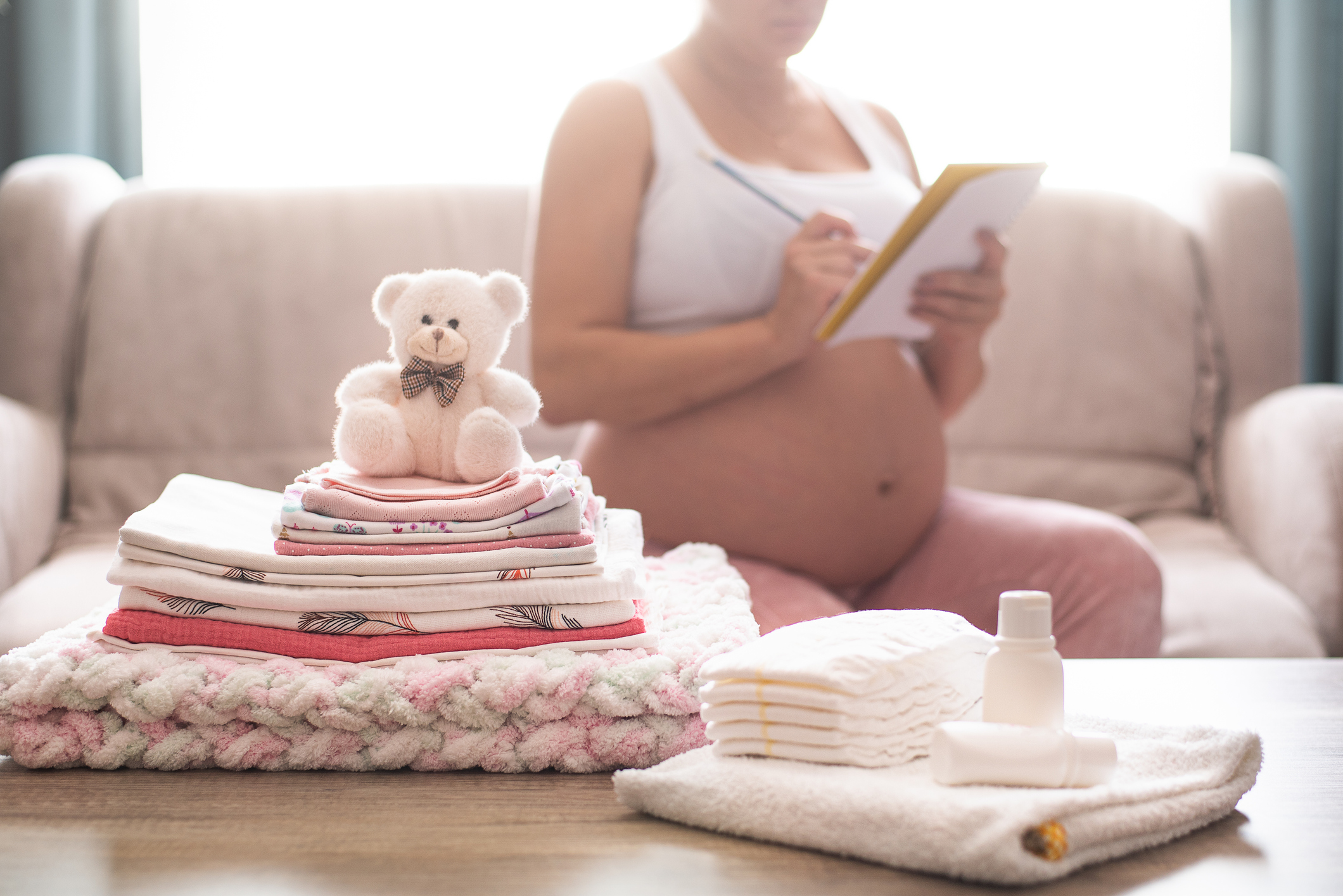 Pregnant woman is getting ready for the maternity hospital, packing baby stuff.