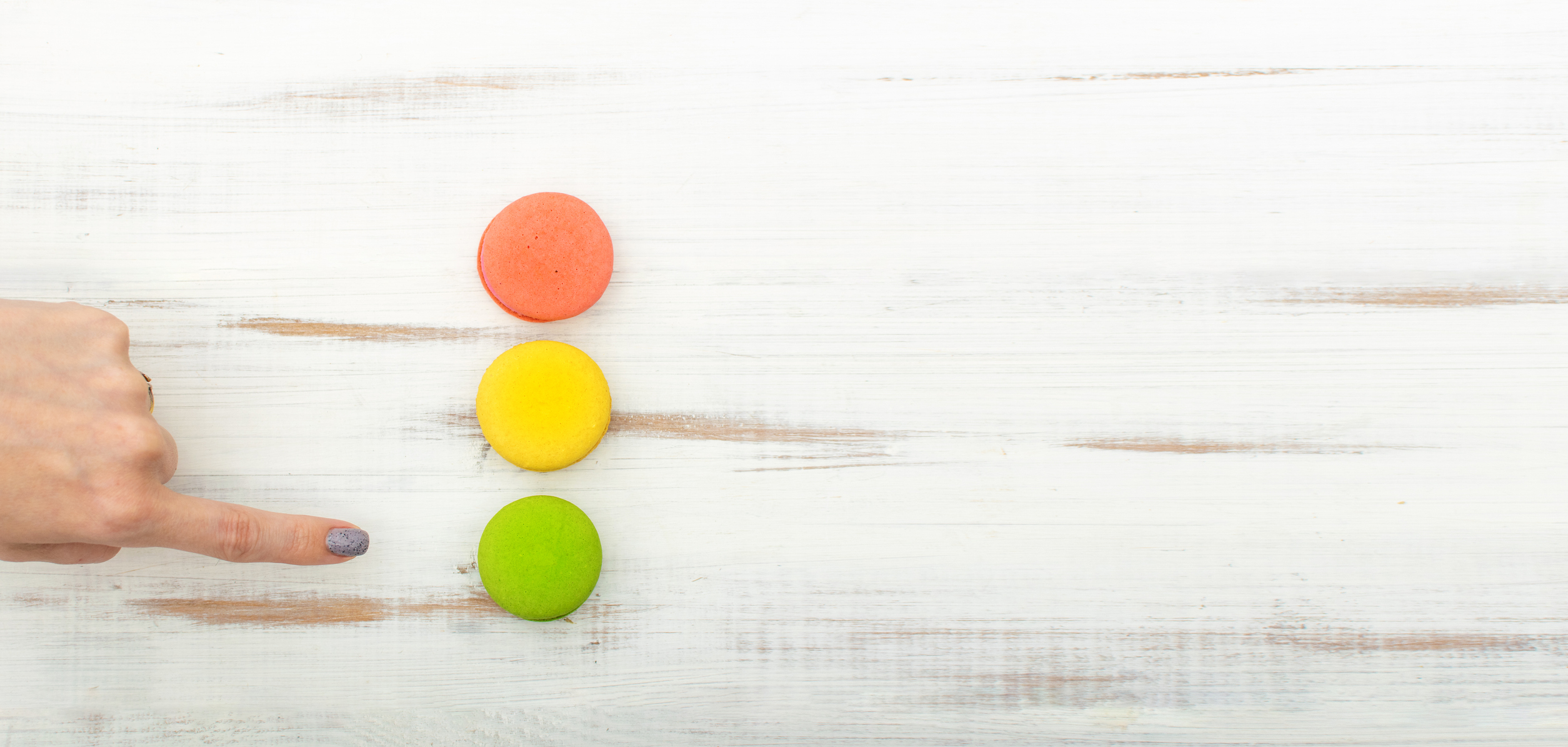 Macaron cake in the form of a traffic light. A woman's finger points to green.