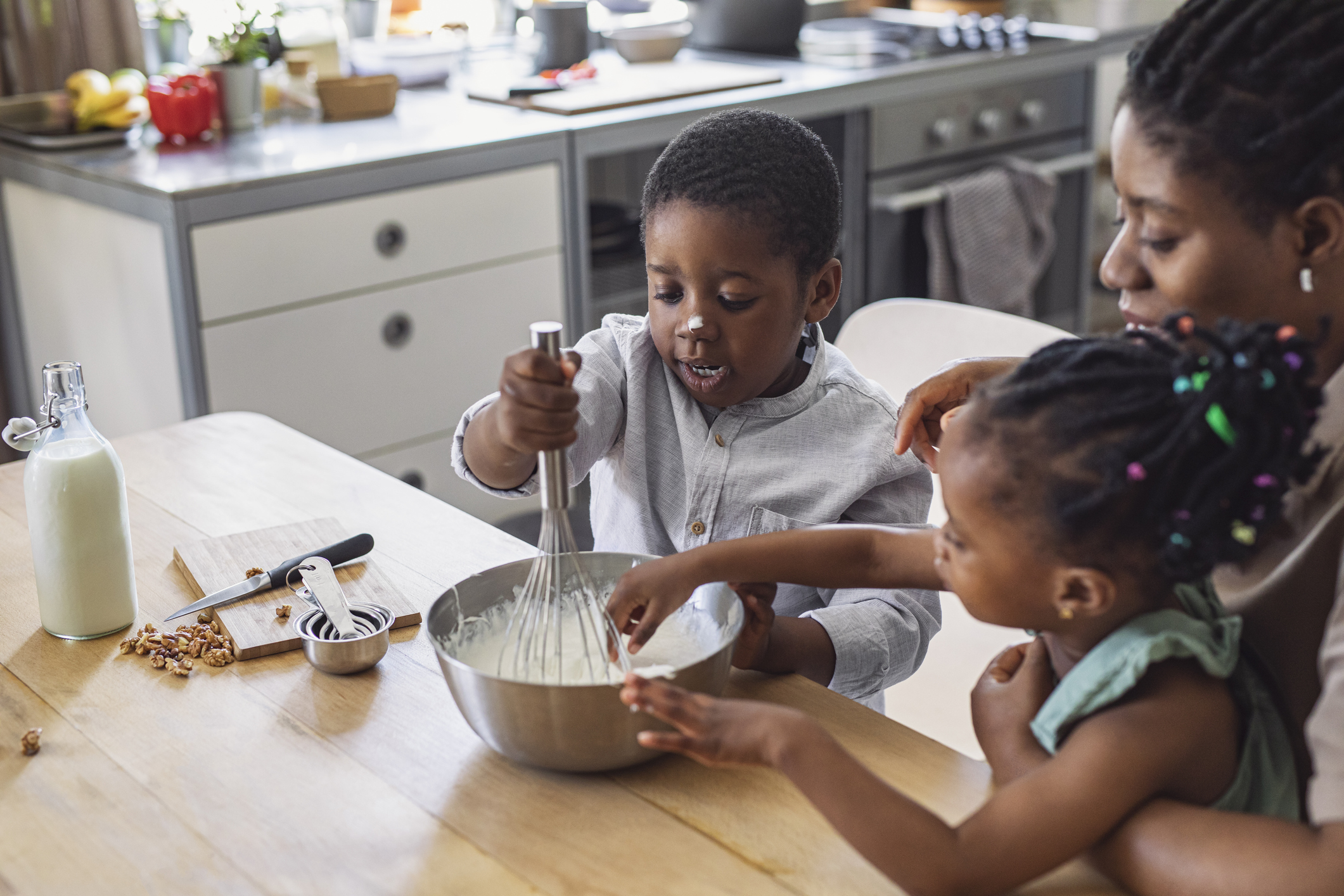 Happy Mother, Daughter and Son Preparing Whipped Cream in a Kitchen