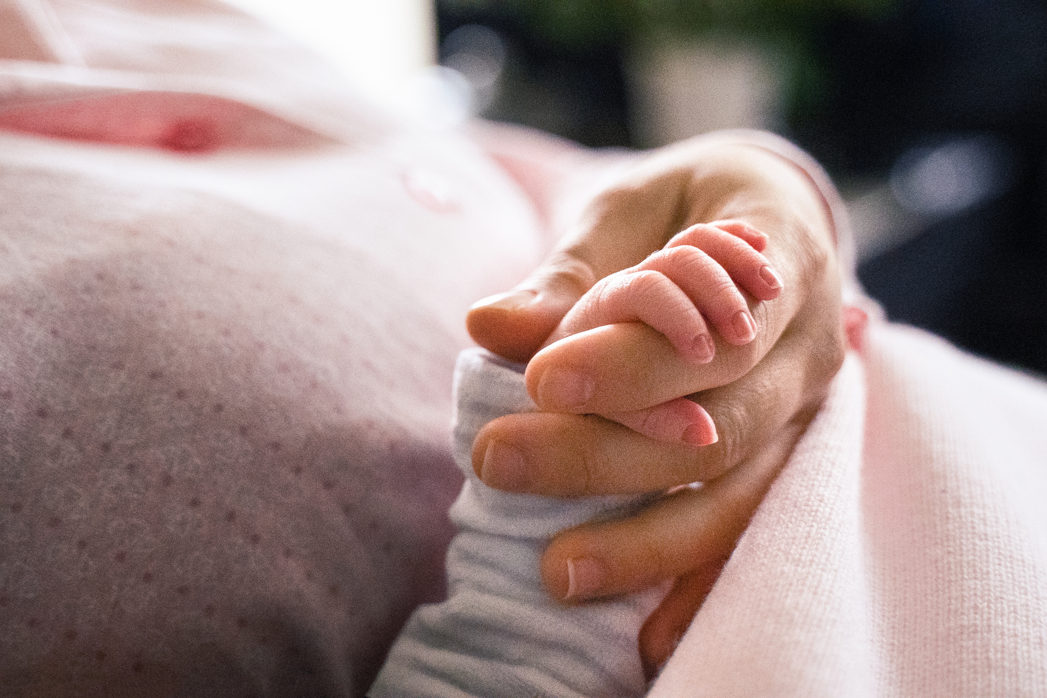 Newborn baby during COVID-19 pandemic. Baby girl holding her mother's finger.