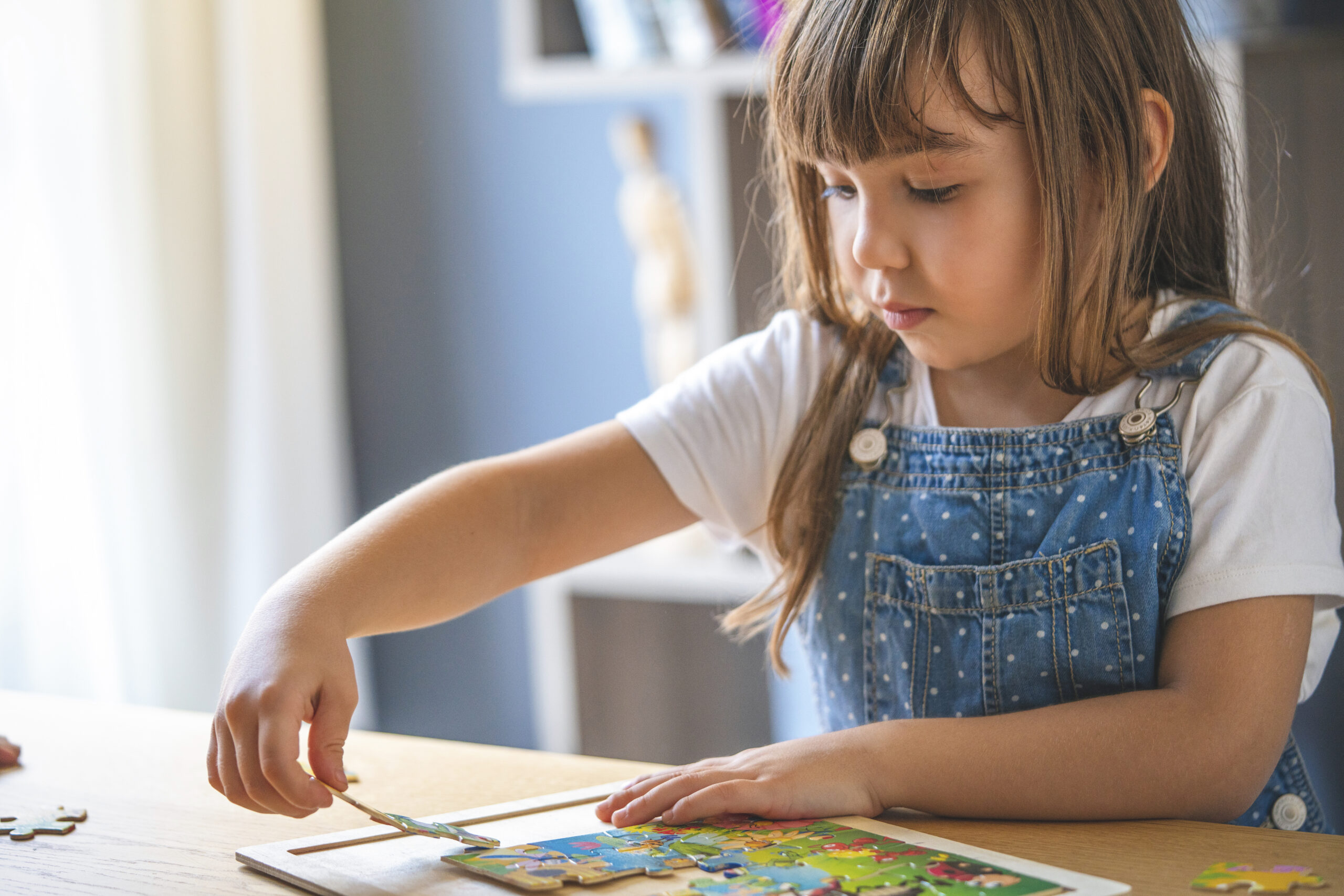 Little girl playing with puzzles at home