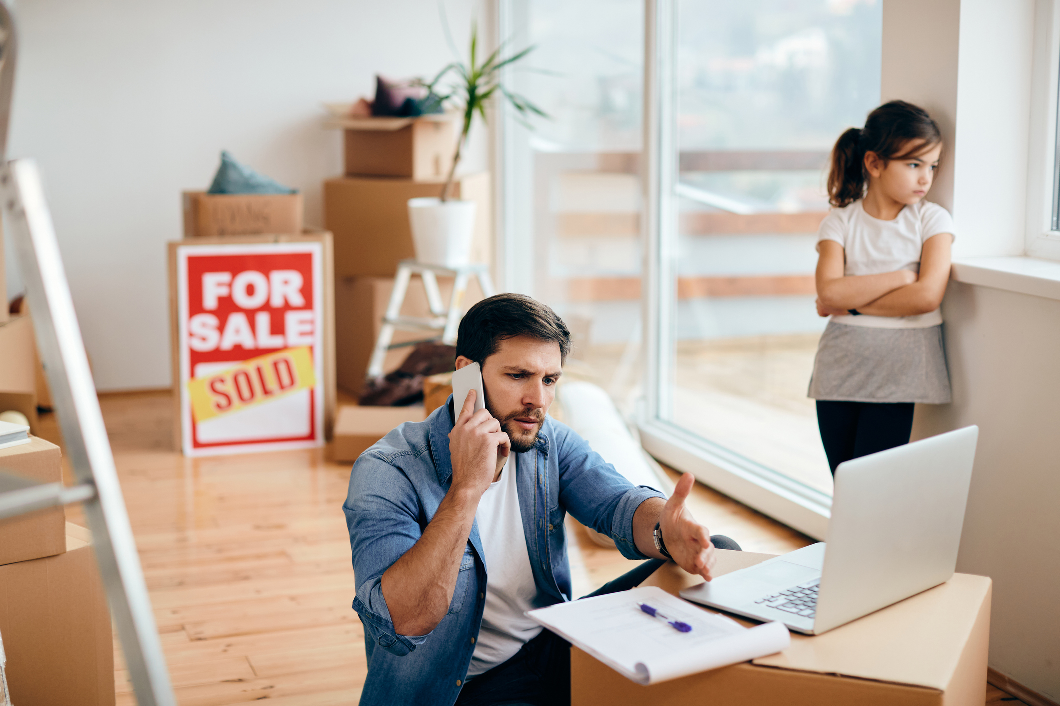 Displeased father talking on the phone while relocating into new home with his daughter.