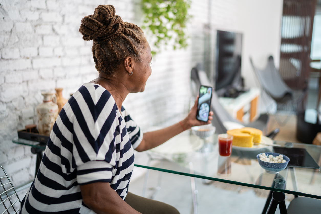 Senior woman using smartphone doing a video call with family at home