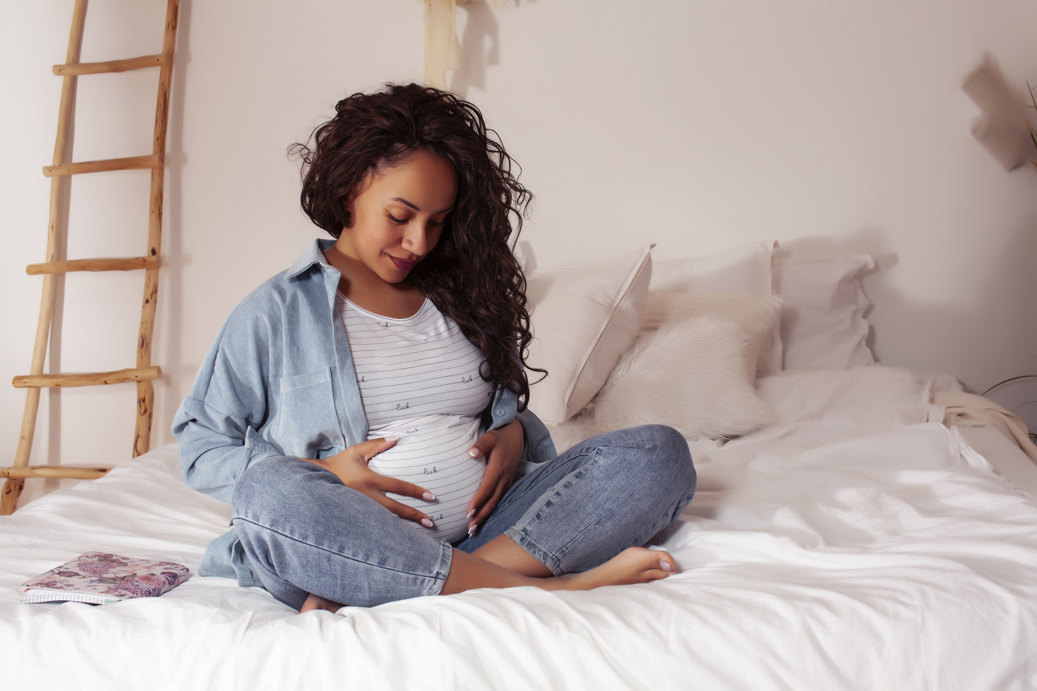 young pretty african american woman pregnant laying in bed, lifestyle people concept