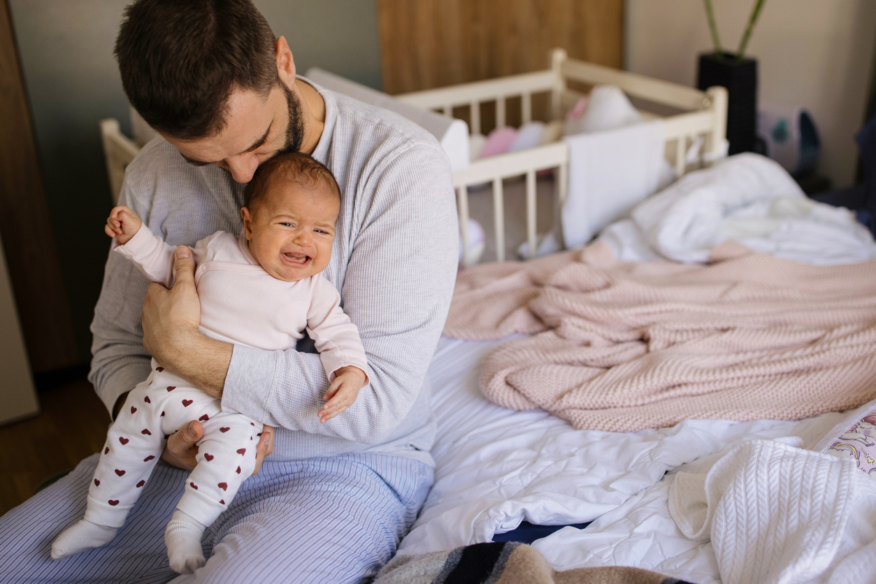 Dad Holding crying baby in the colic carry