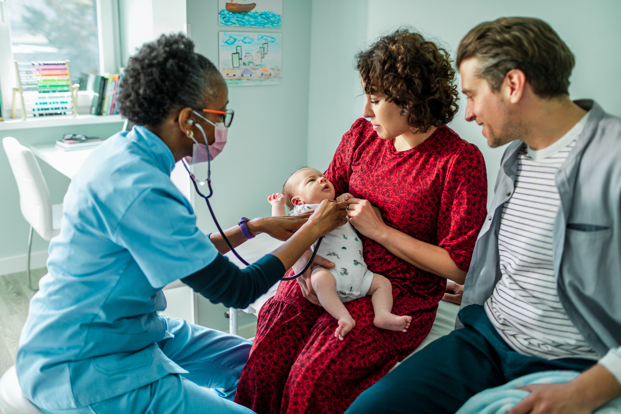 Pediatrician using a stethoscope on a newborn baby