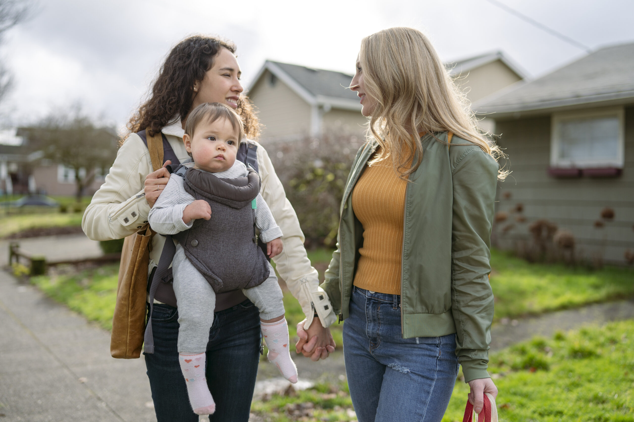 Cute baby girl riding in baby carrier while enjoying the outdoors with her moms