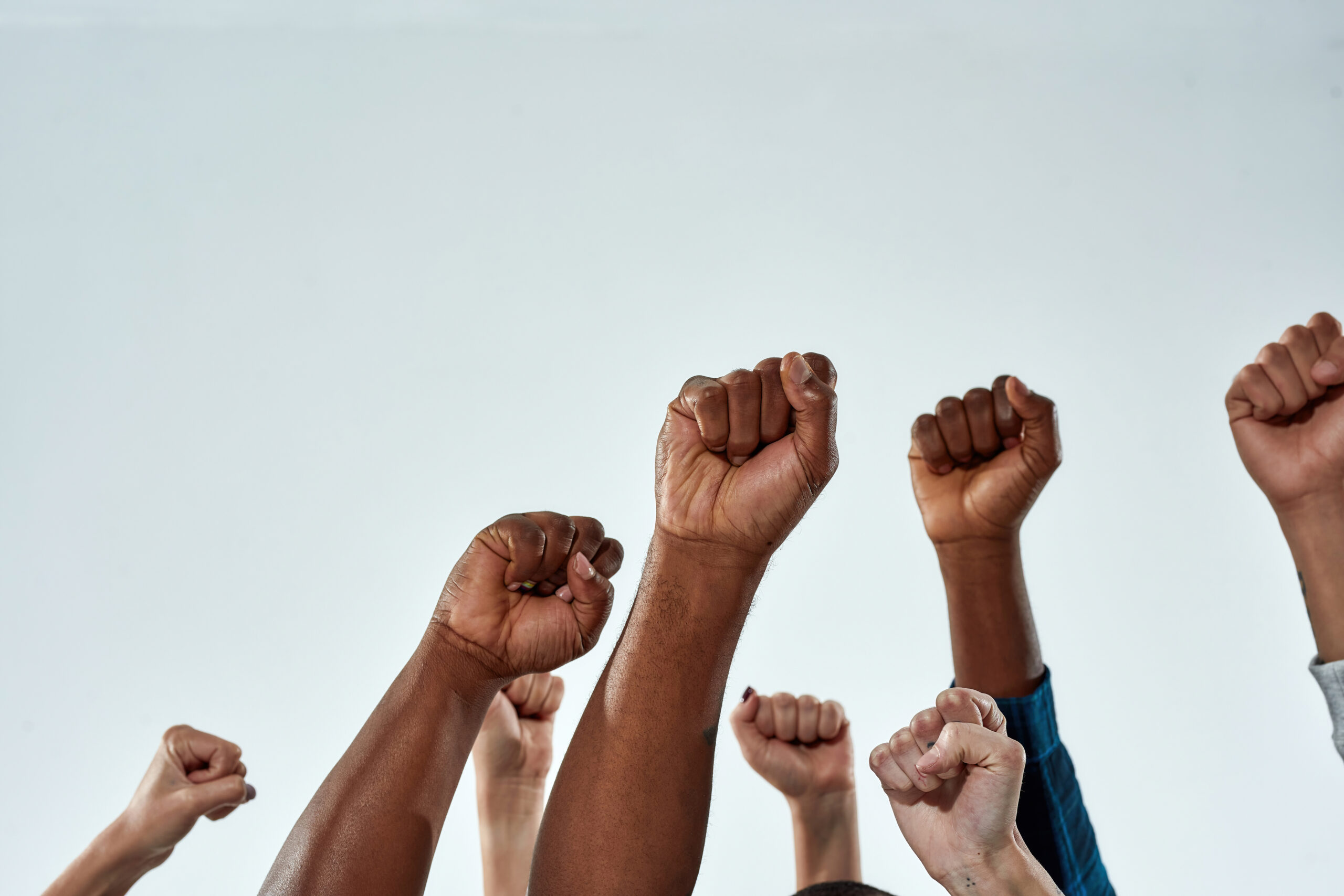 Raised hands of multiracial people clenched into fists