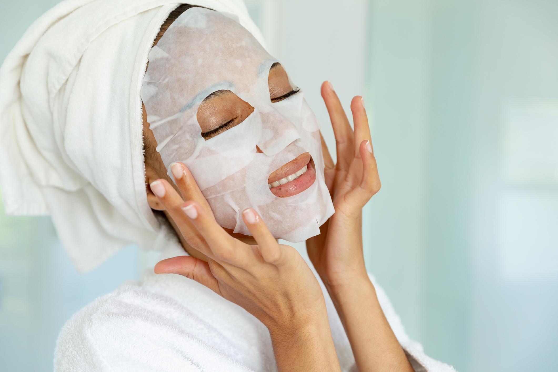 Mixed race woman wearing bathrobe and cleansing face mask in bathroom