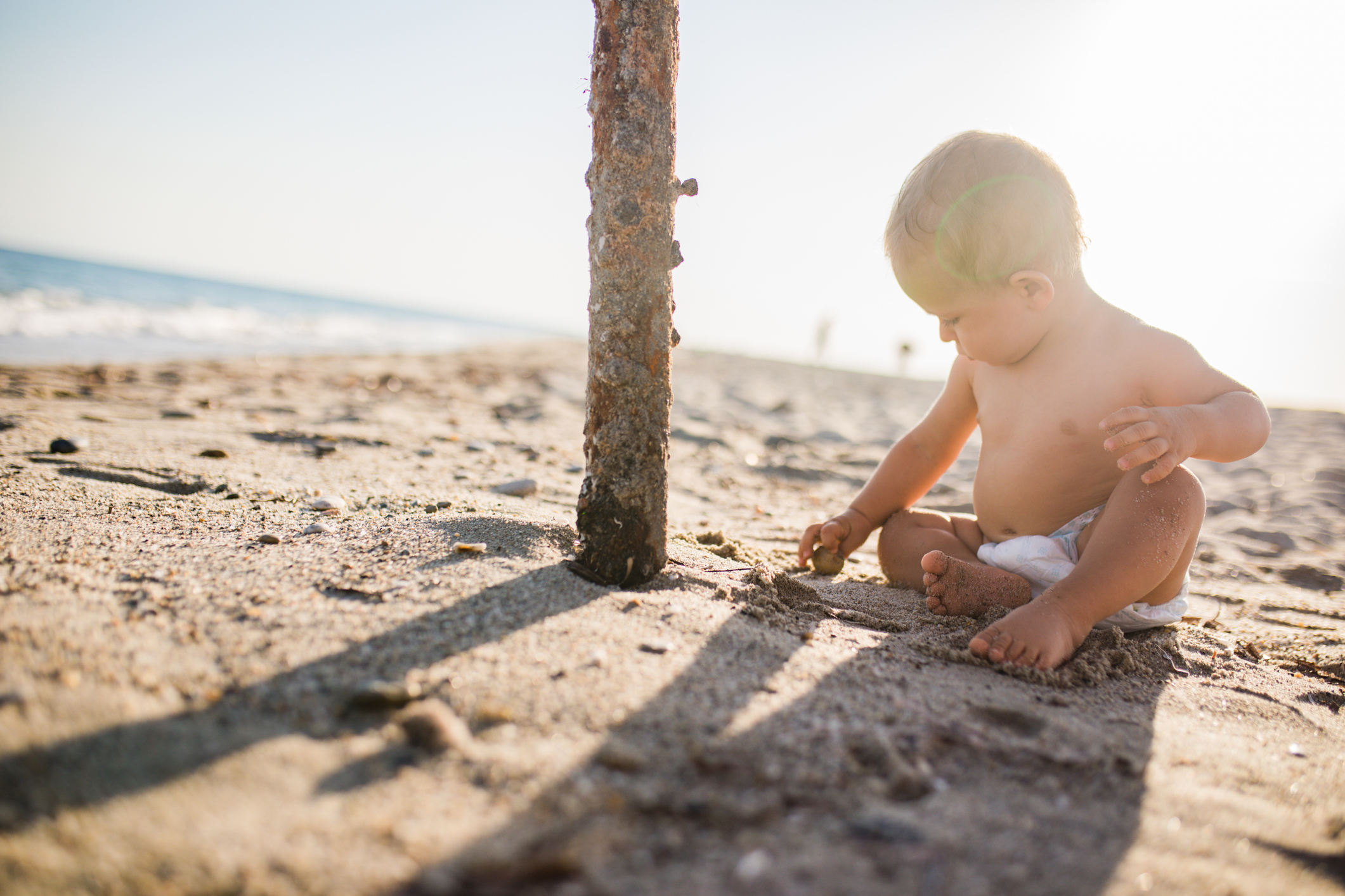 Little baby boy sitting on the sand