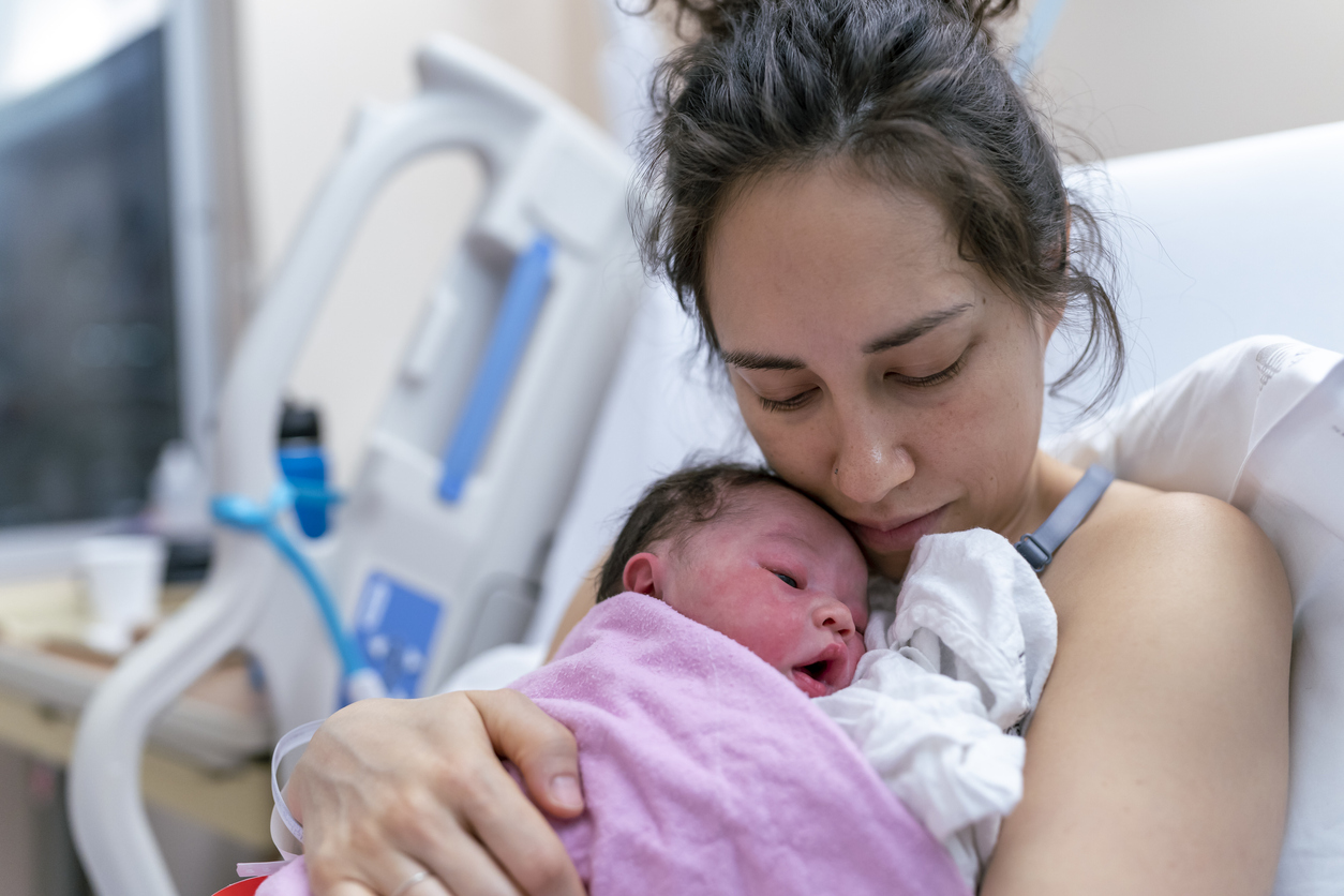 Mixed Race Mother Snuggling Newborn After Delivery