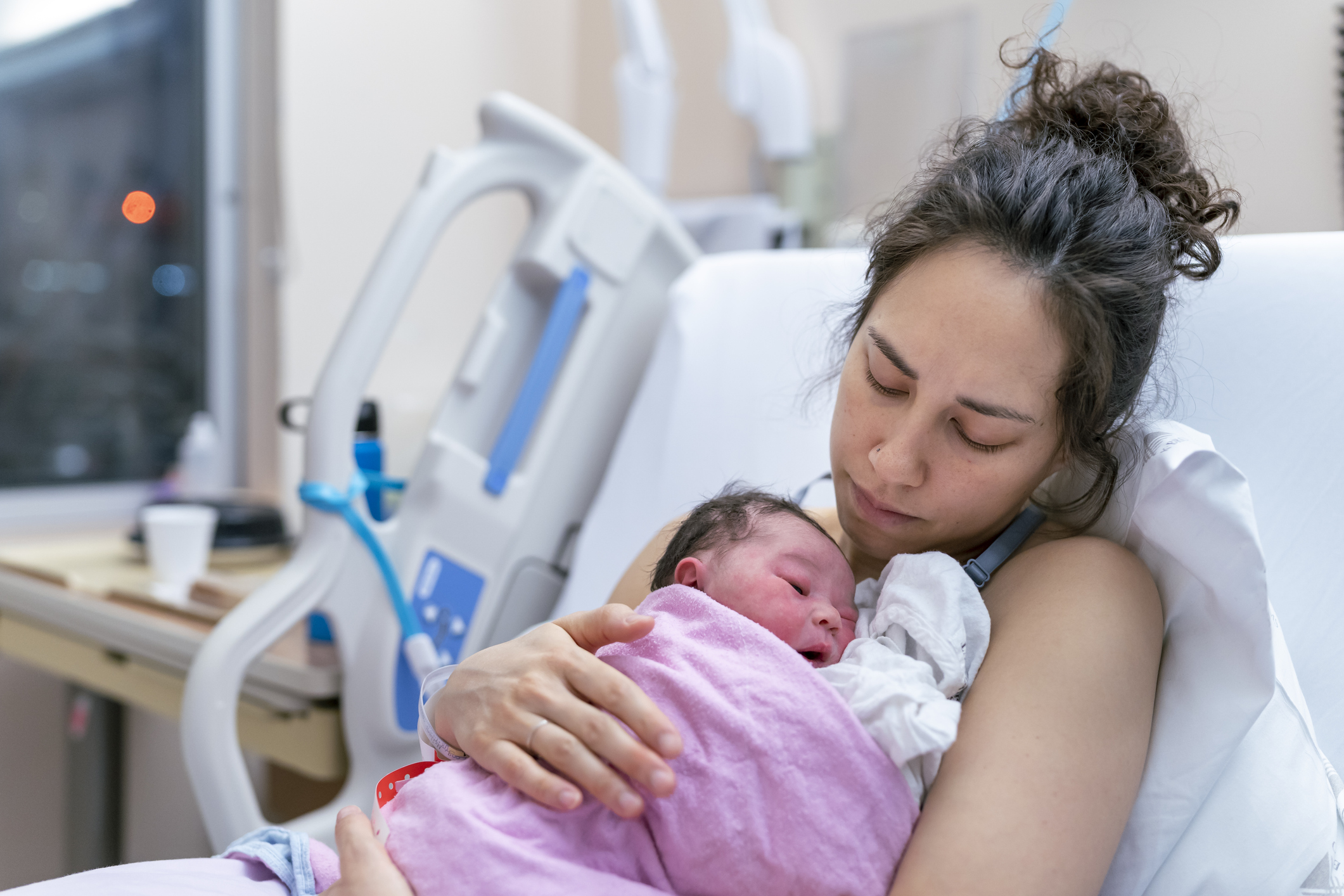 Mixed Race Mother Snuggling Newborn After Delivery