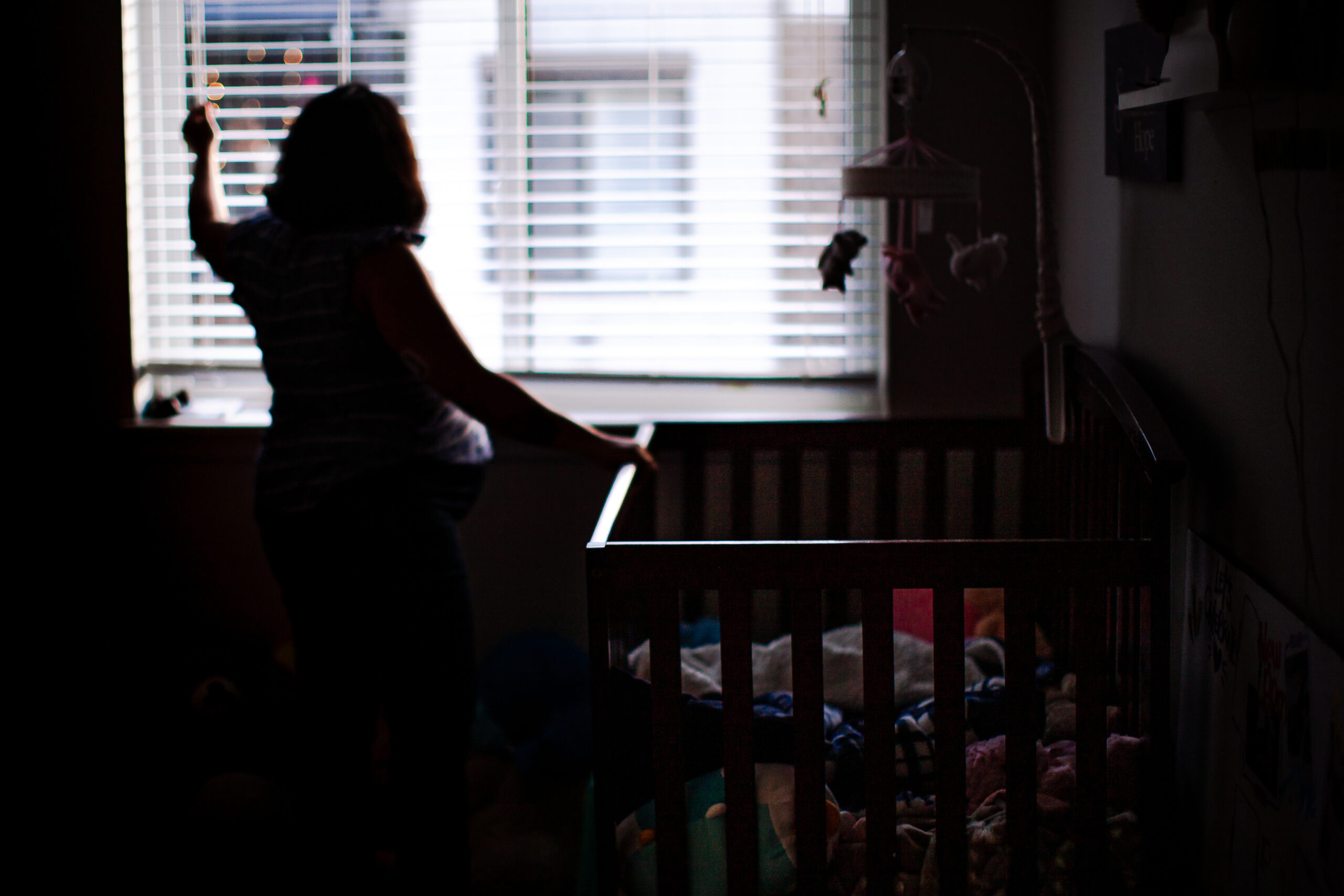 Mother closes window shades for bedtime for the kids