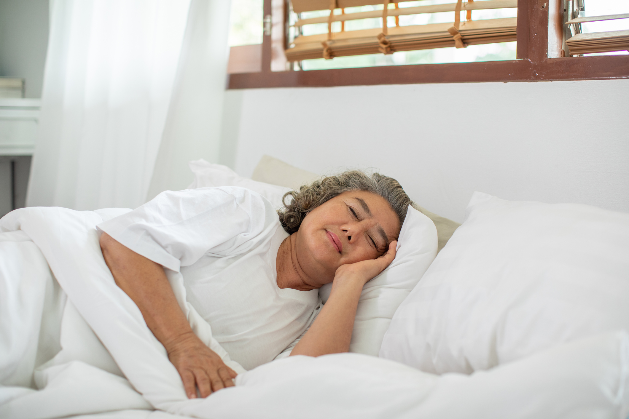 Asian Elderly woman with white hairs close eyes smile sleep and sweet dream on bed in cozy bedroom in the morning feeling so relax and comfortable,Healthcare and Sleep Concept