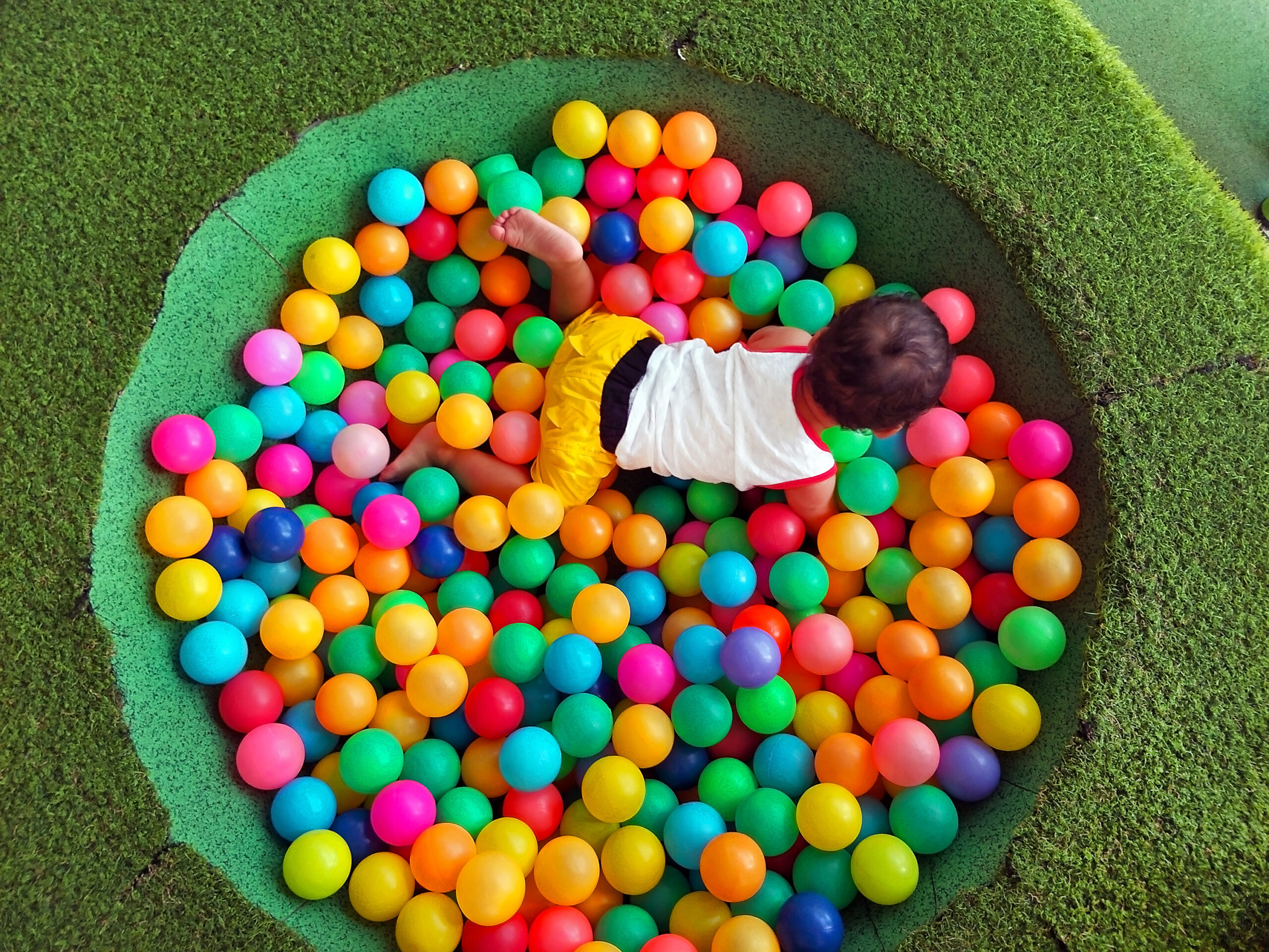 kid enjoy playing in the private grass ball pool