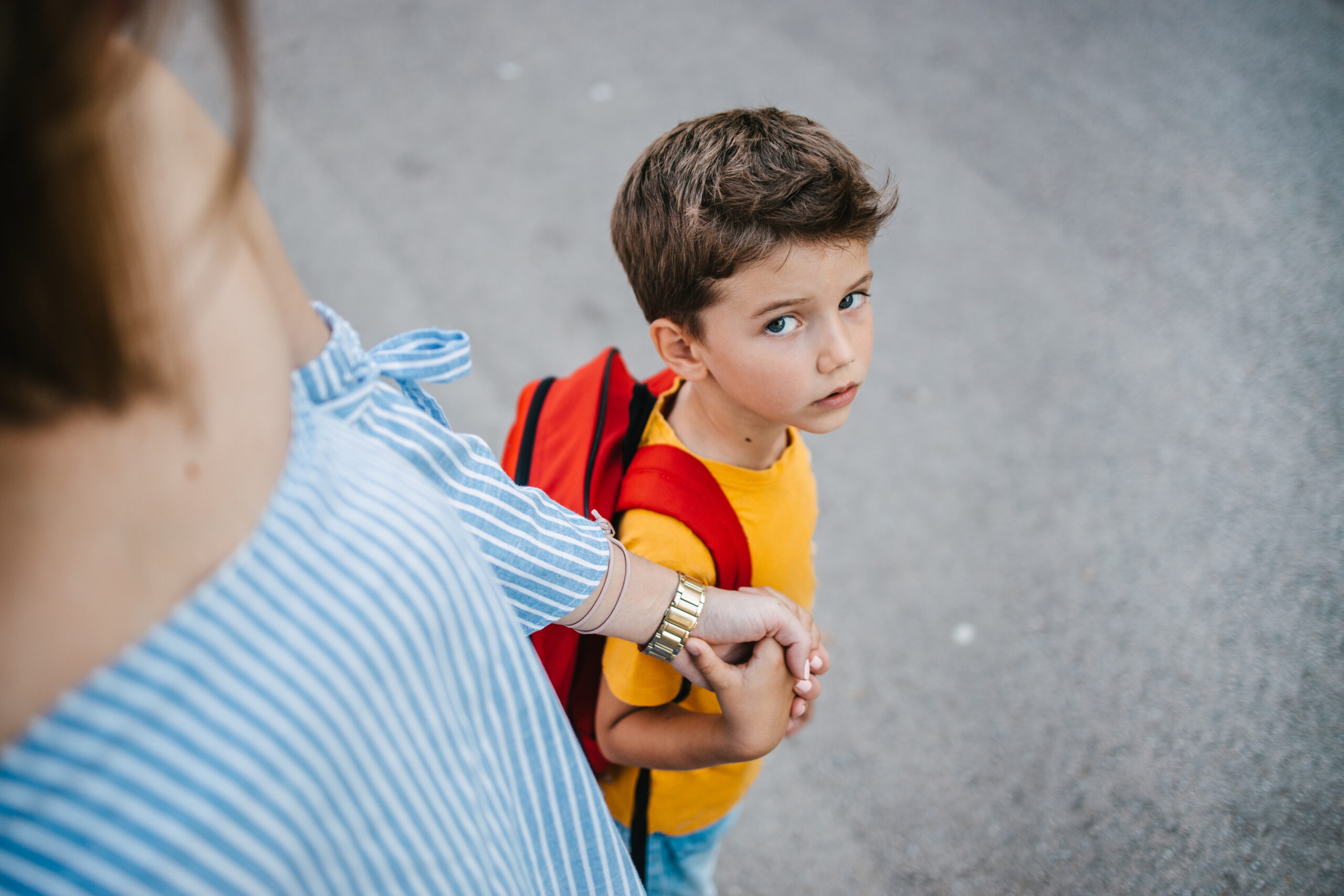 Mother holding her son's hand sending him to school