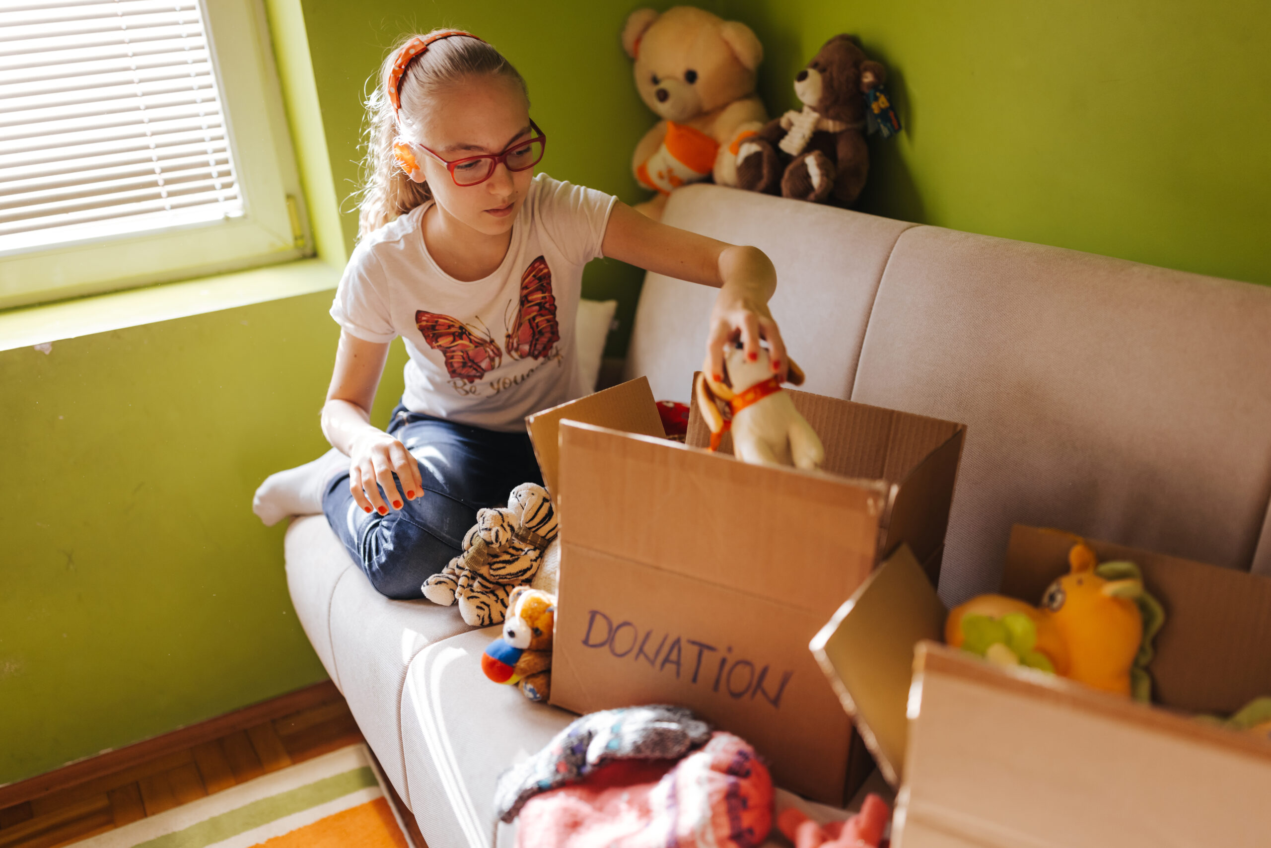 Cute girl sorting toys for donation at home