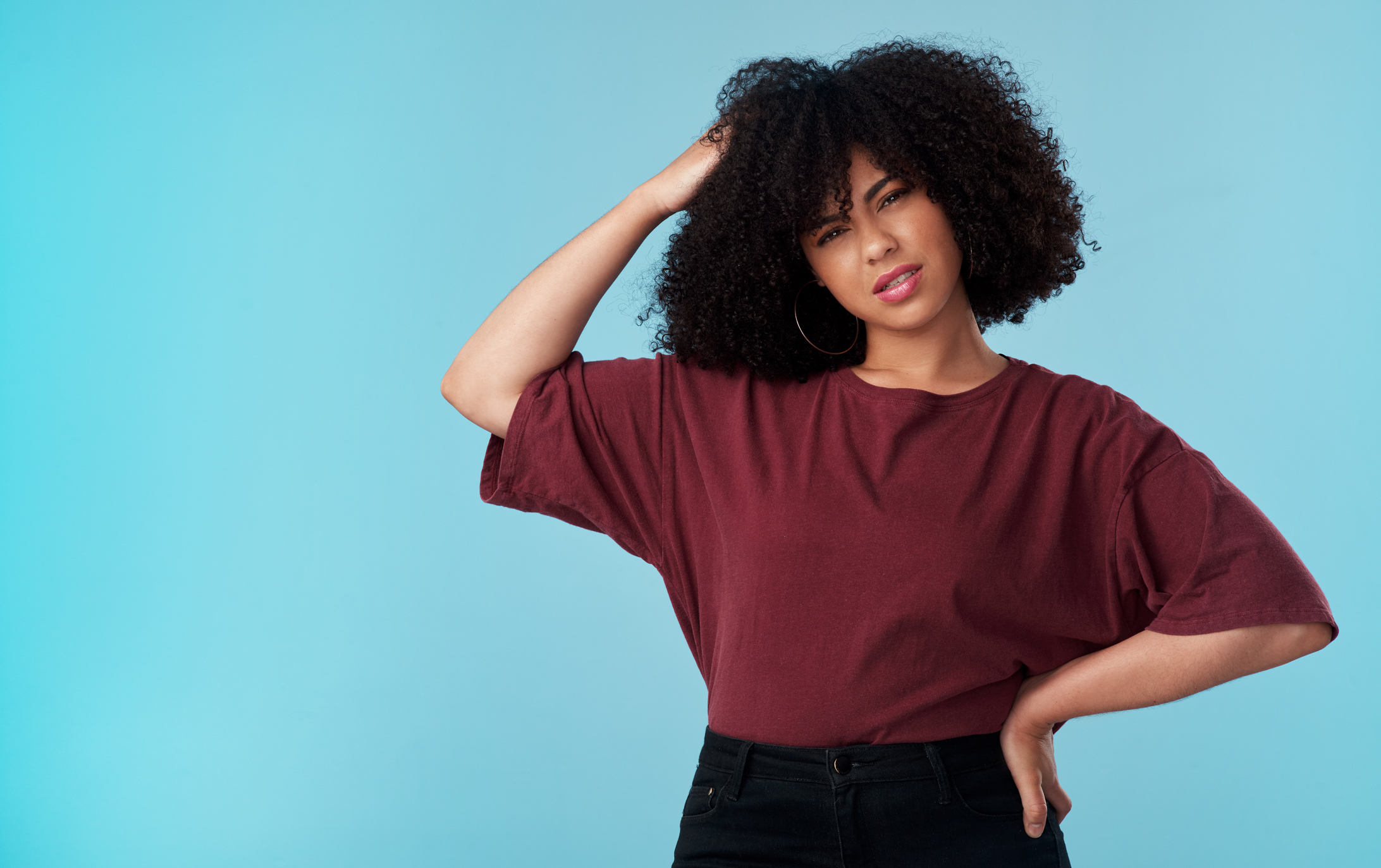 Studio shot of a young woman looking confused against a blue background