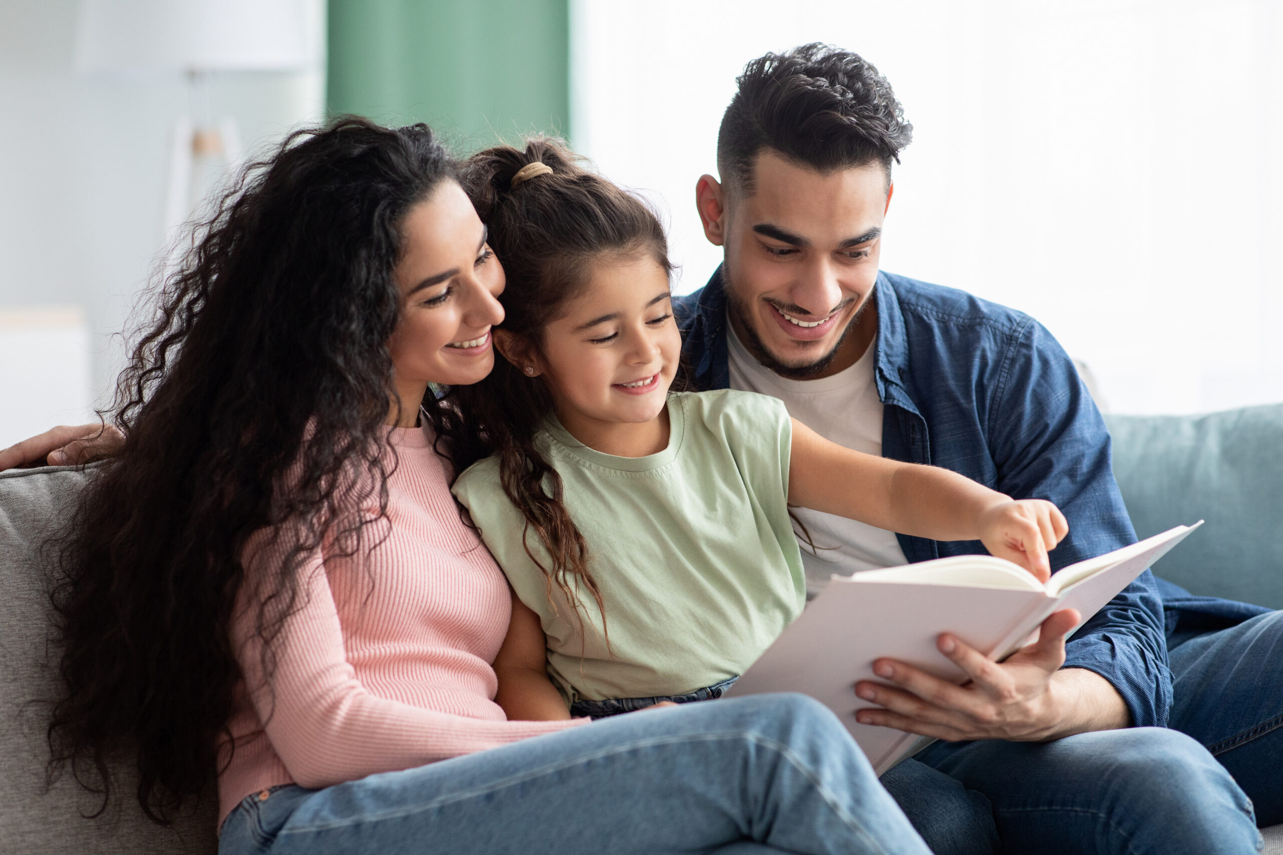 Parenting Concept. Happy Young Arab Parents Reading Book With Their Child