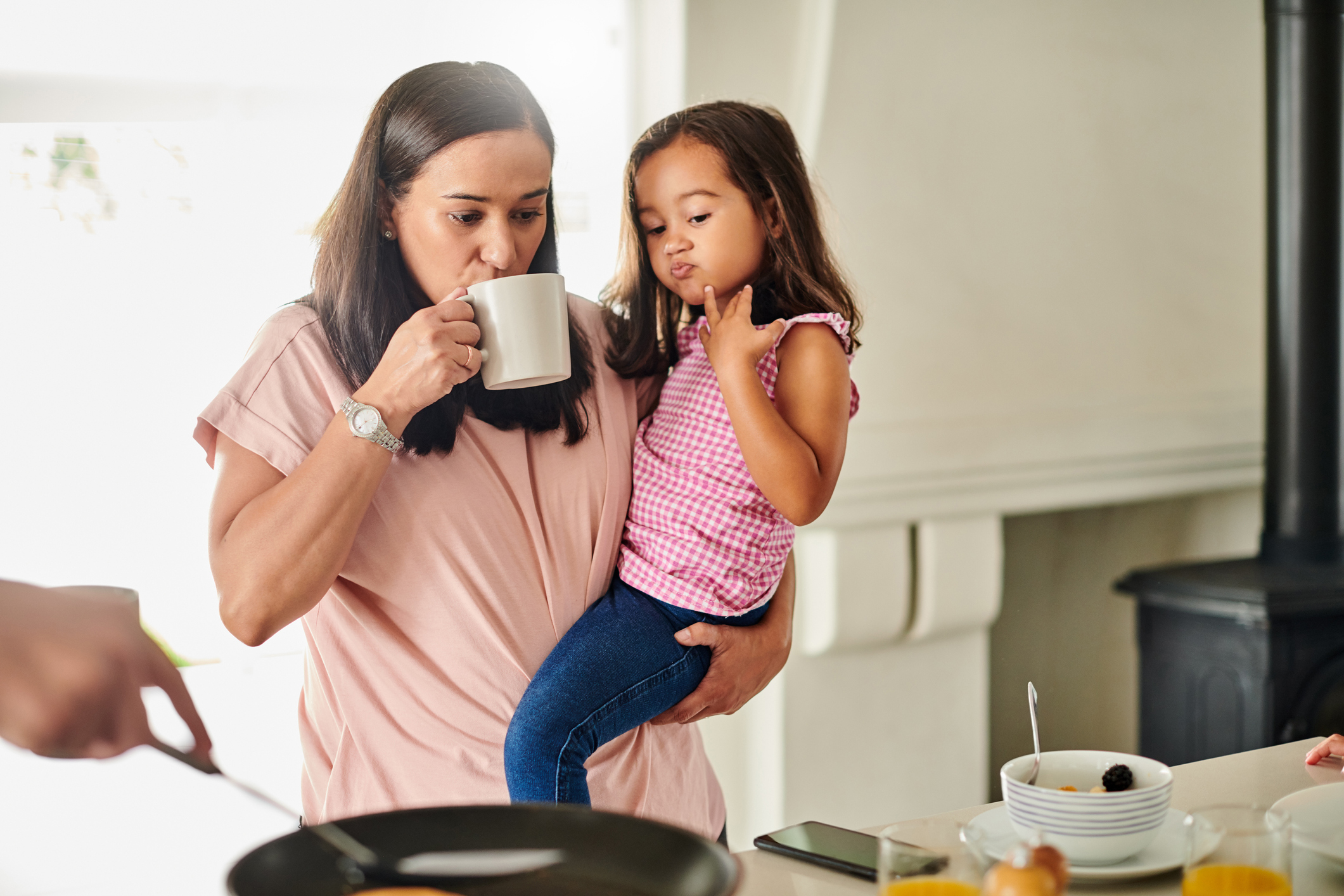 Shot of a young woman carrying her daughter and having coffee in the morning at home