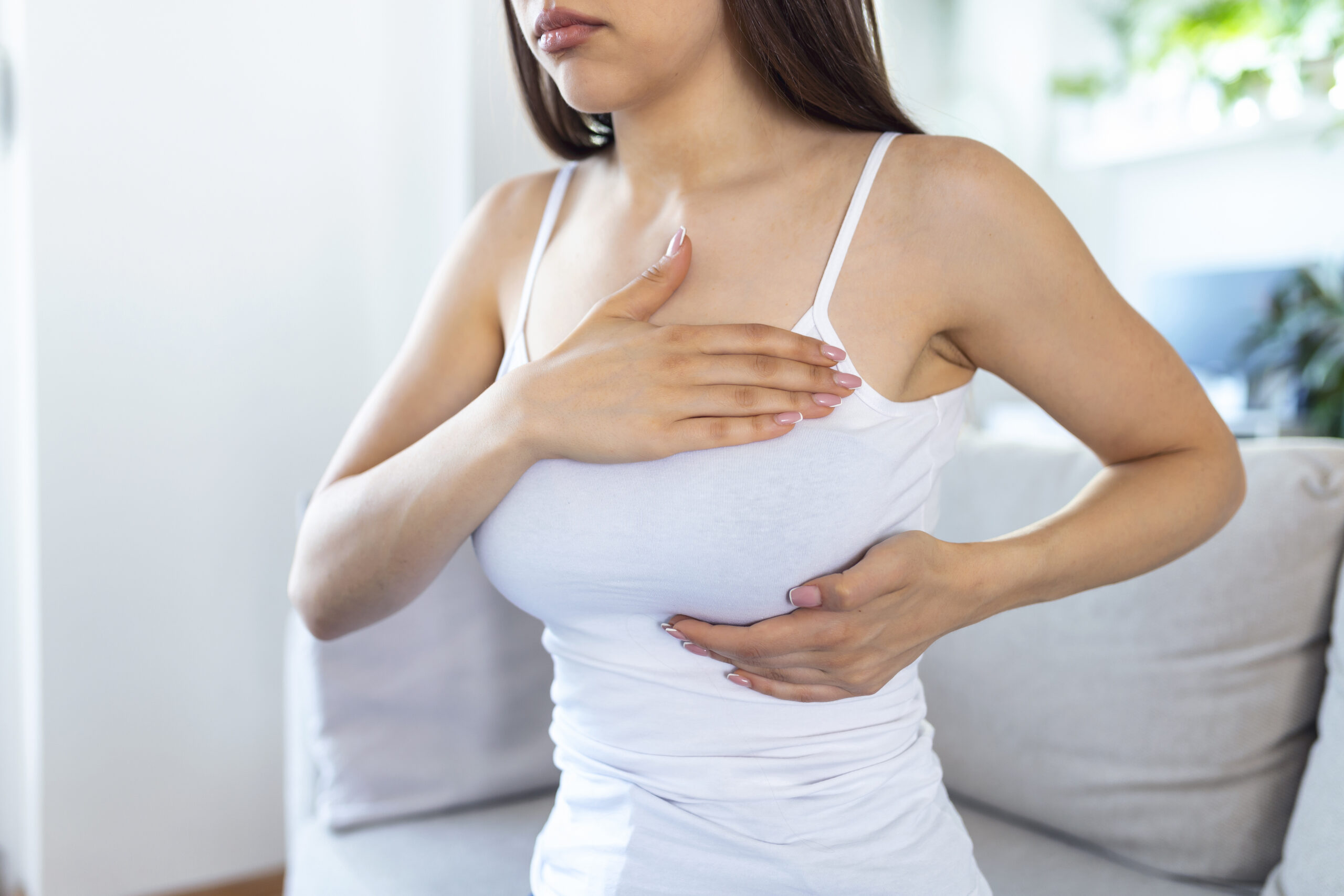 Young caucasian woman palpating her breast by herself that she concern about breast cancer. Healthcare and breast cancer concept