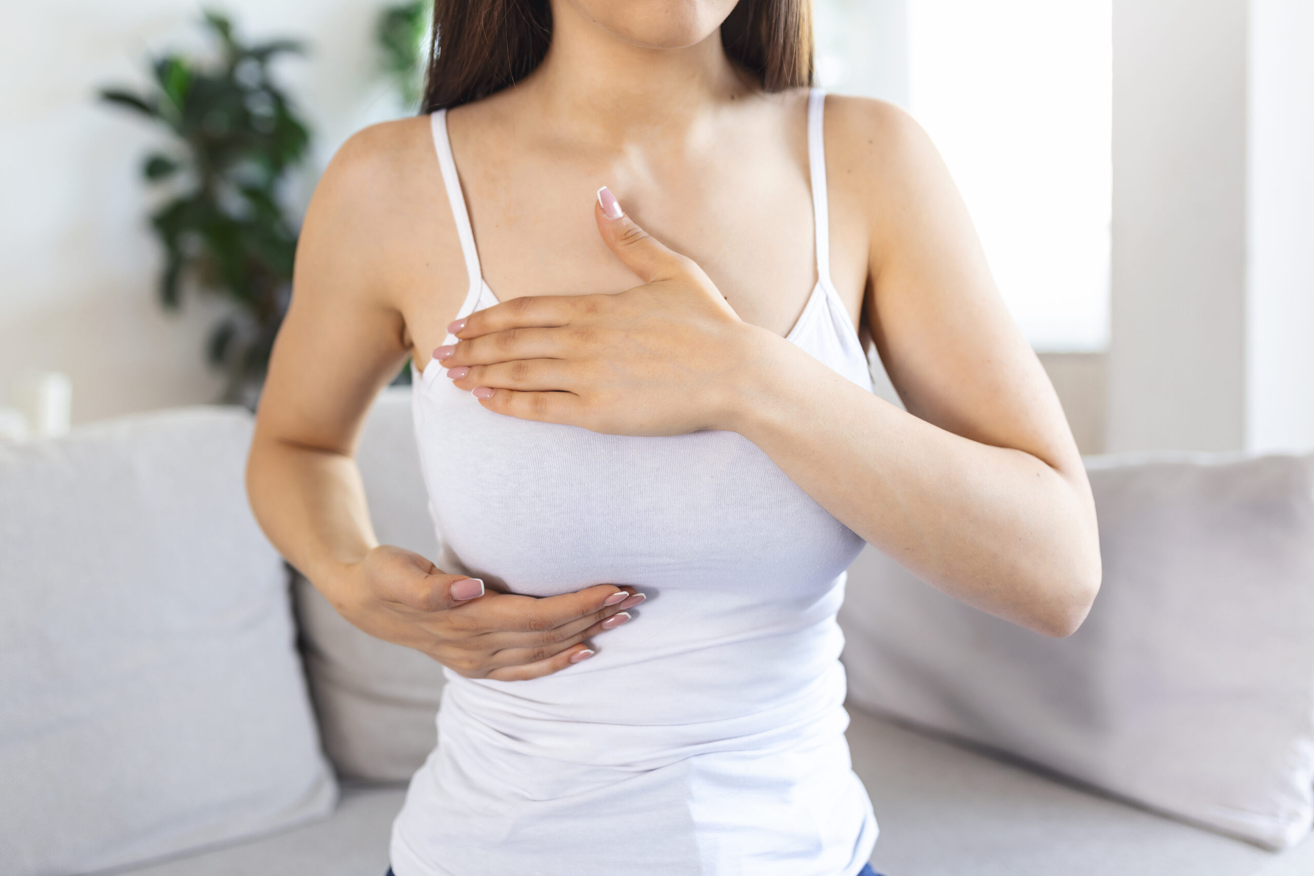 Young caucasian woman palpating her breast by herself that she concern about breast cancer. Healthcare and breast cancer concept