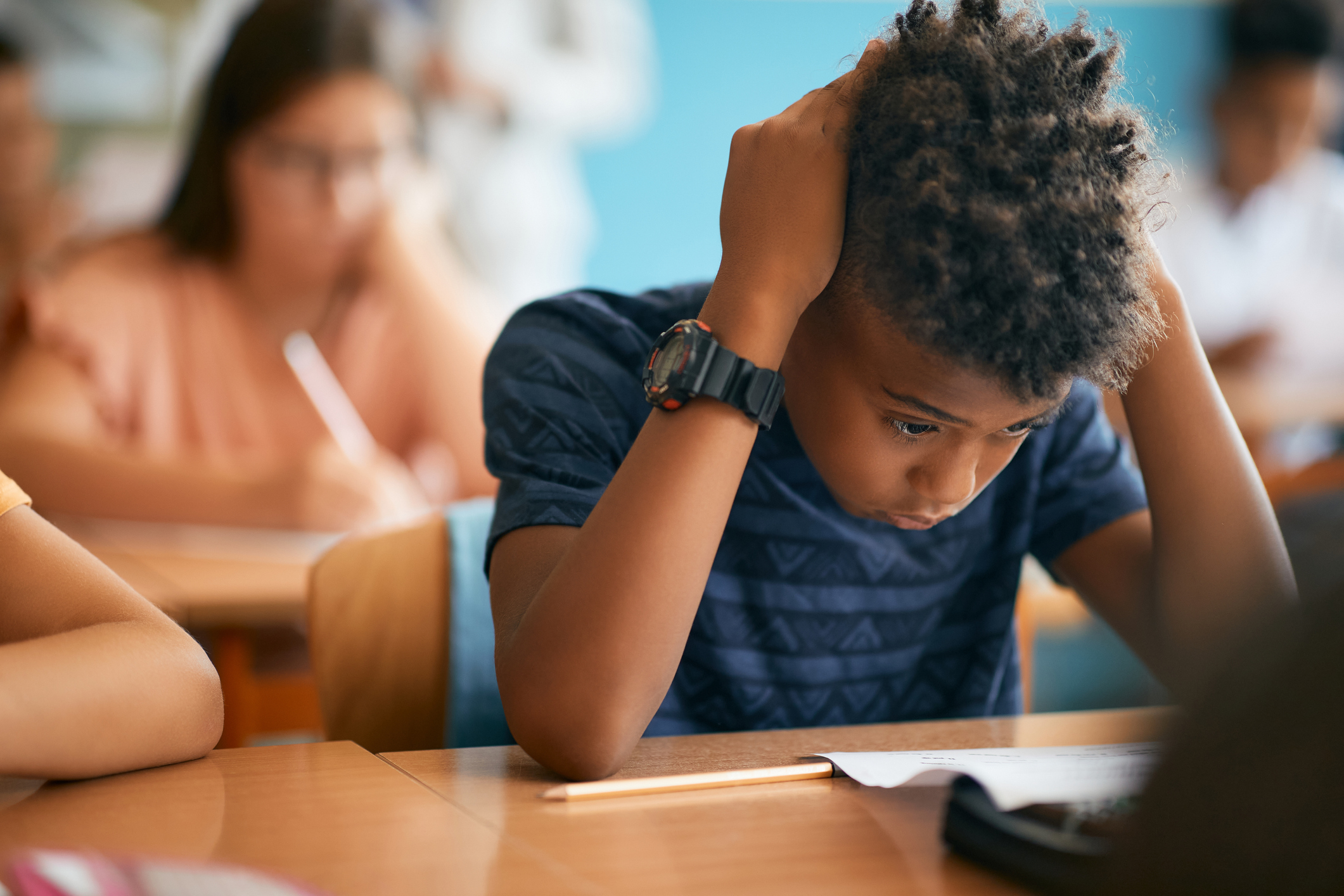 Uncertain African American schoolboy having exam during a class in the classroom.