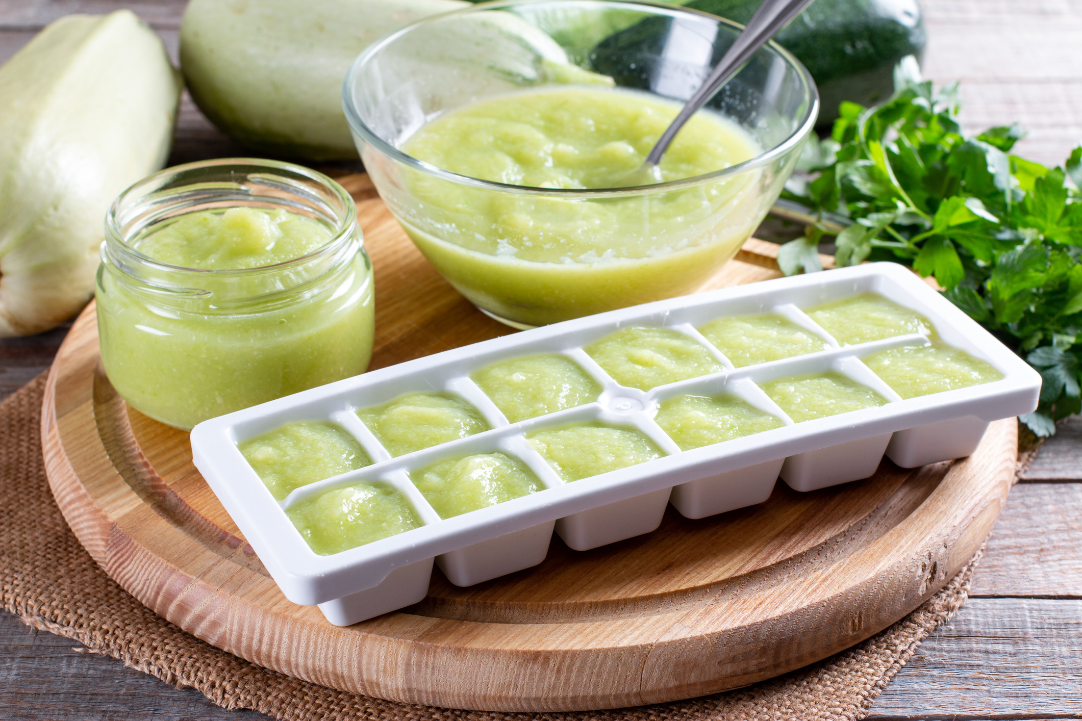 Zucchini puree in ice cube trays ready for freezing on a cutting board on a table. Frozen Food Concept.