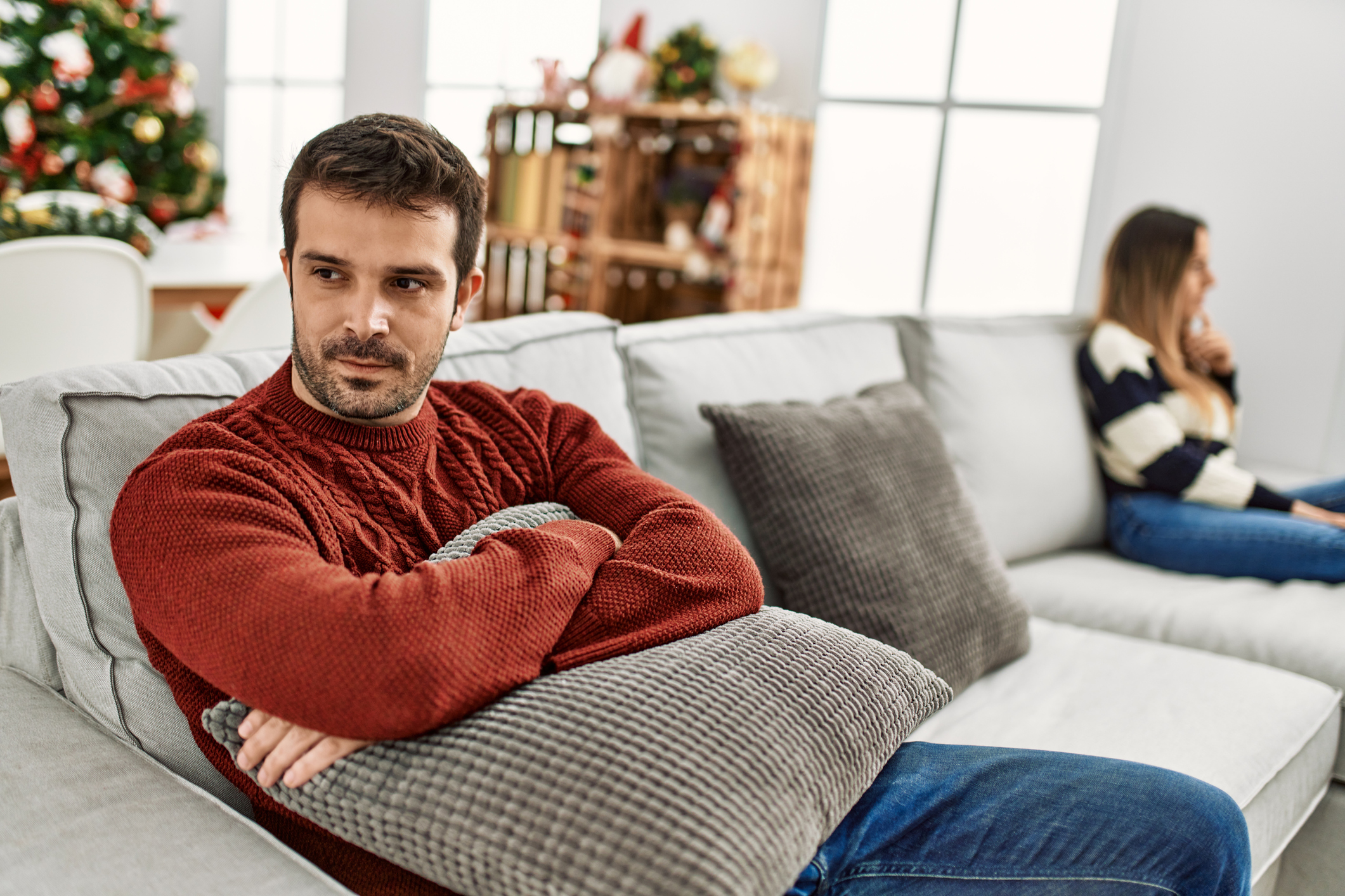 Young hispanic couple with problems sitting on the sofa in silence at home.