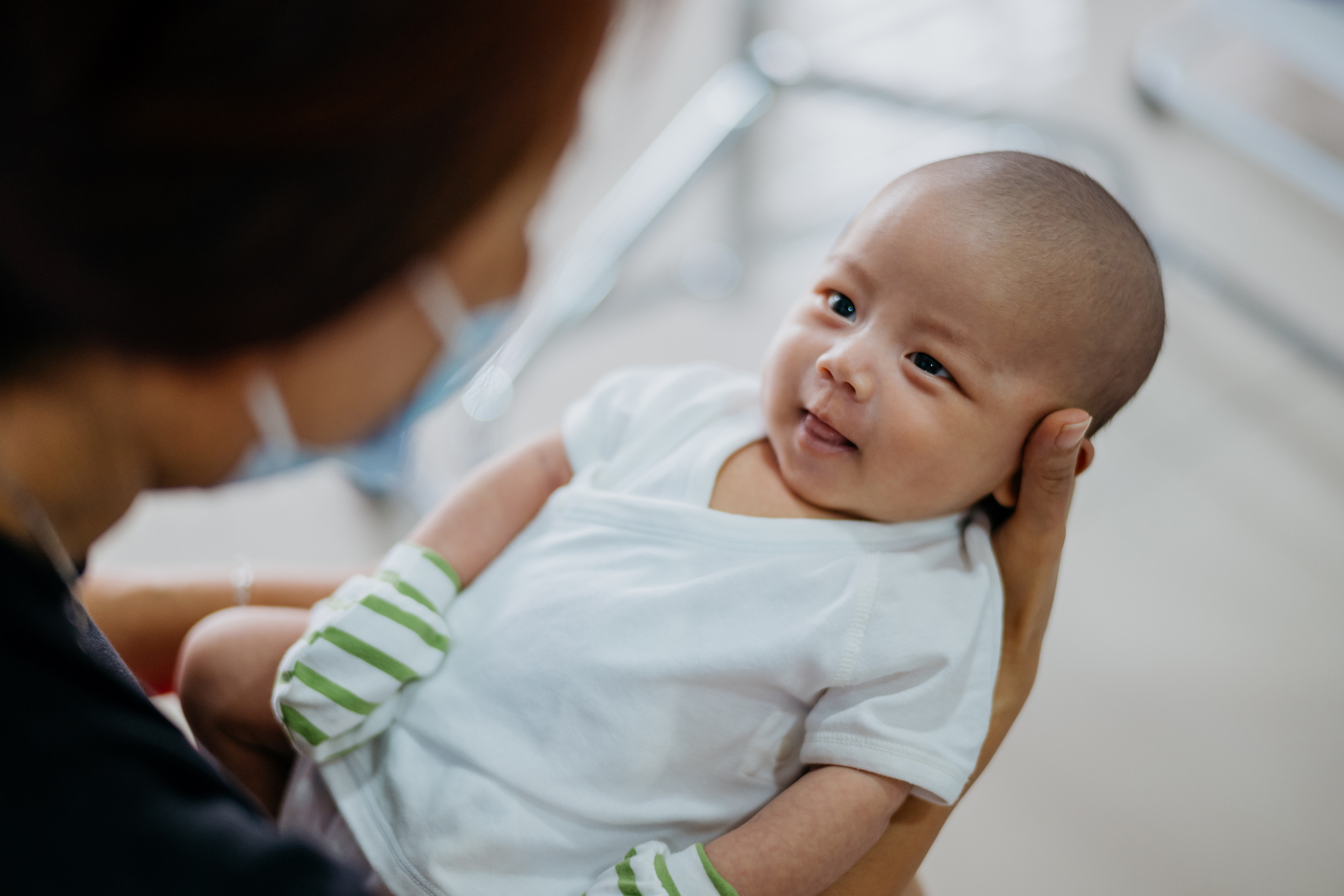 Asian woman carrying a smiling baby boy