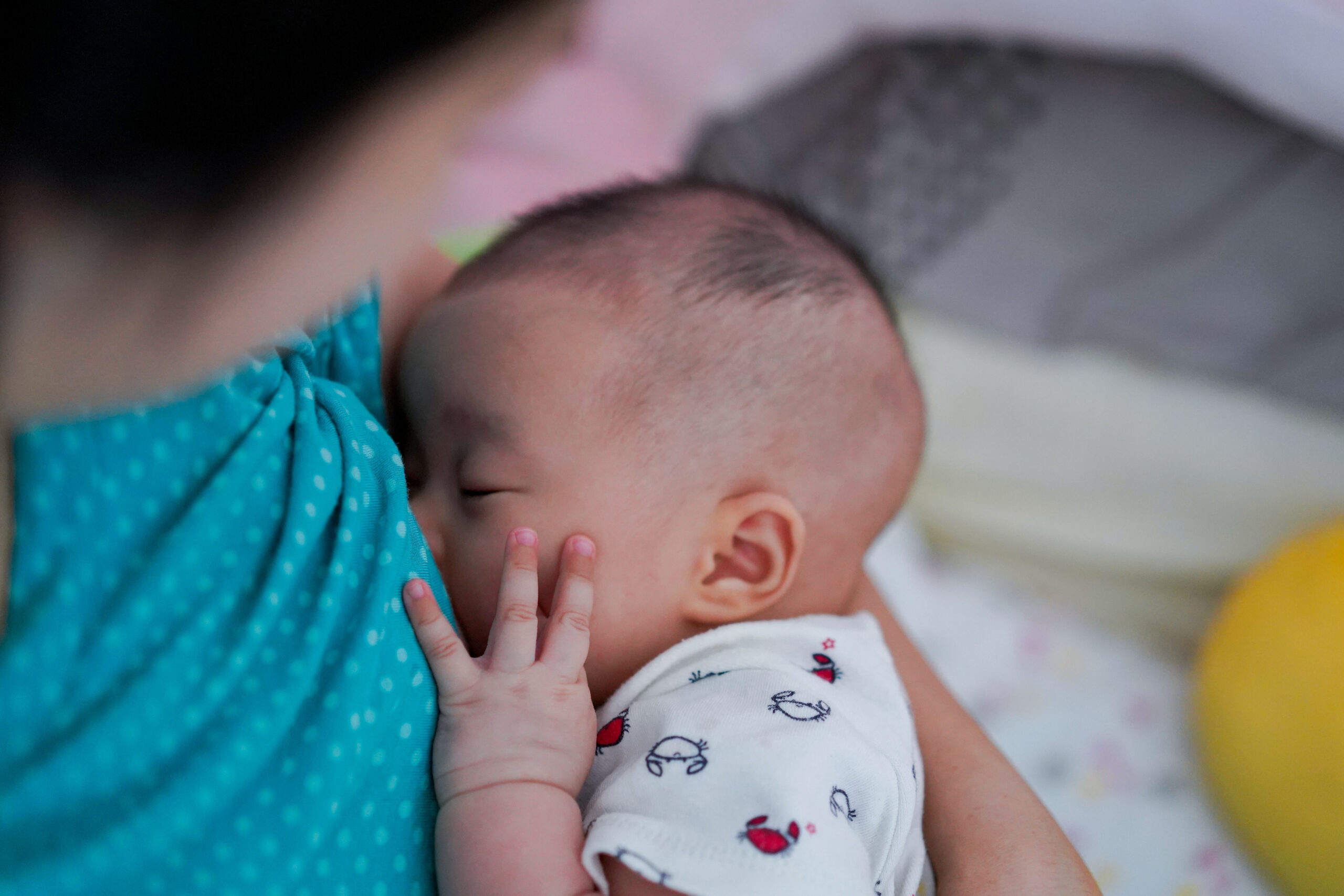 Mother breastfeeding and hugging baby. Asian mom breast feeding her child.Baby hold her hand on face while eating milk before sleeping.