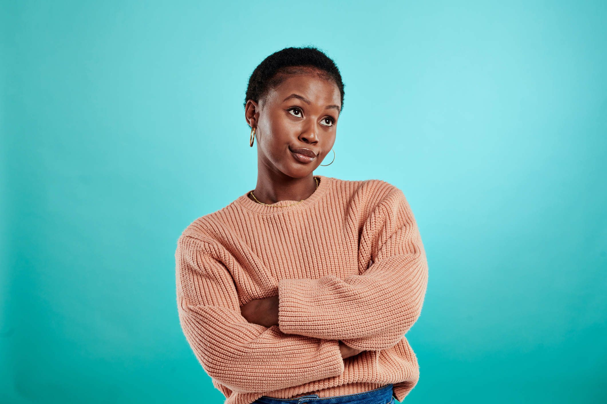 Shot of a woman standing with her arms crossed against a turquoise background