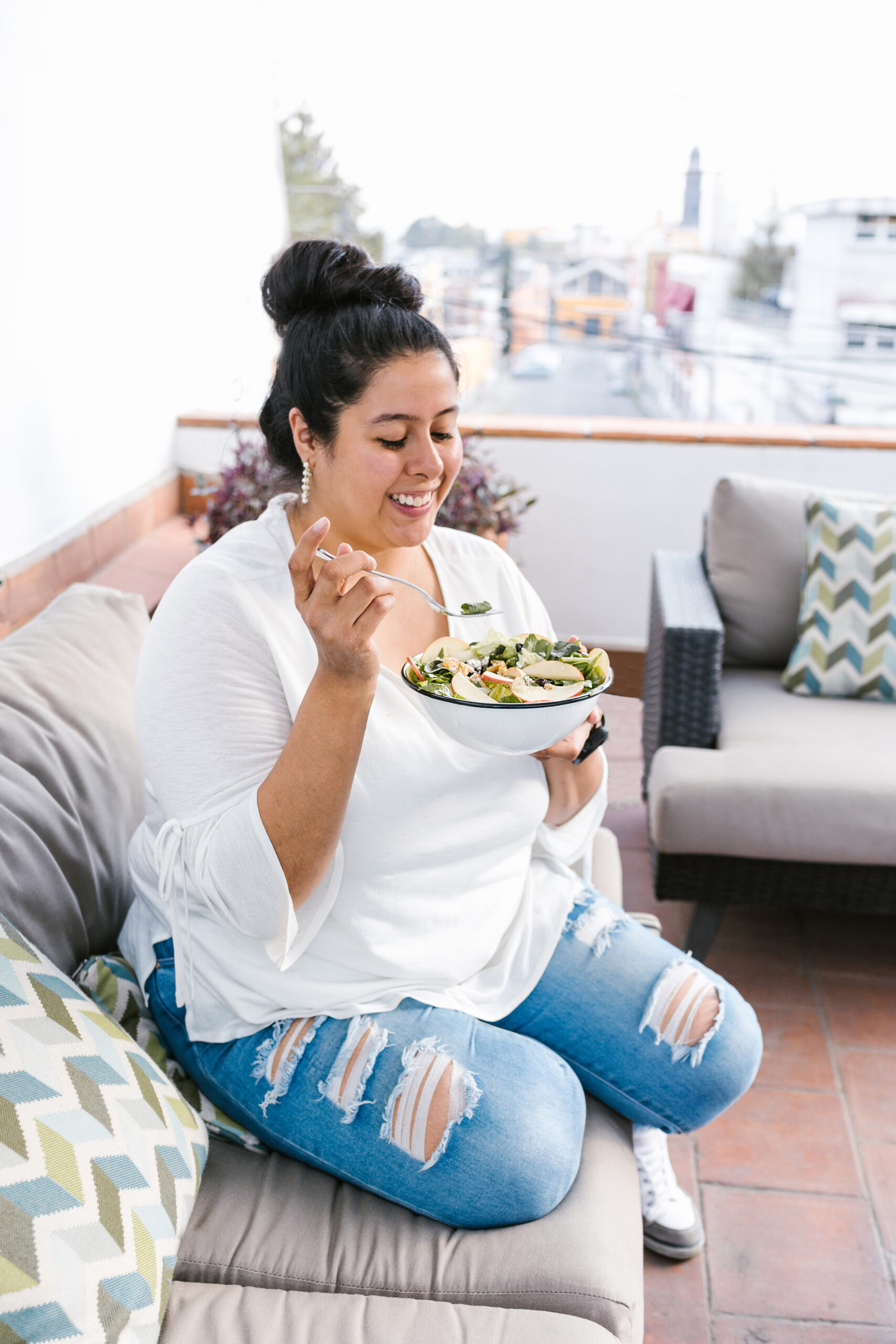 Young curvy mexican woman eating salad sitting on the terrace in Latin America