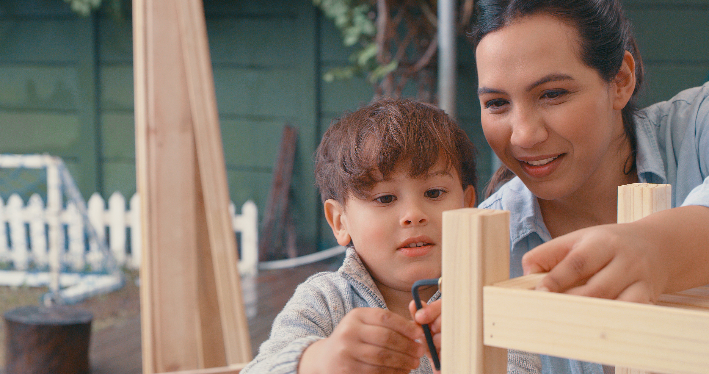 Shot of a young woman working on a wooden project with her son in their backyard