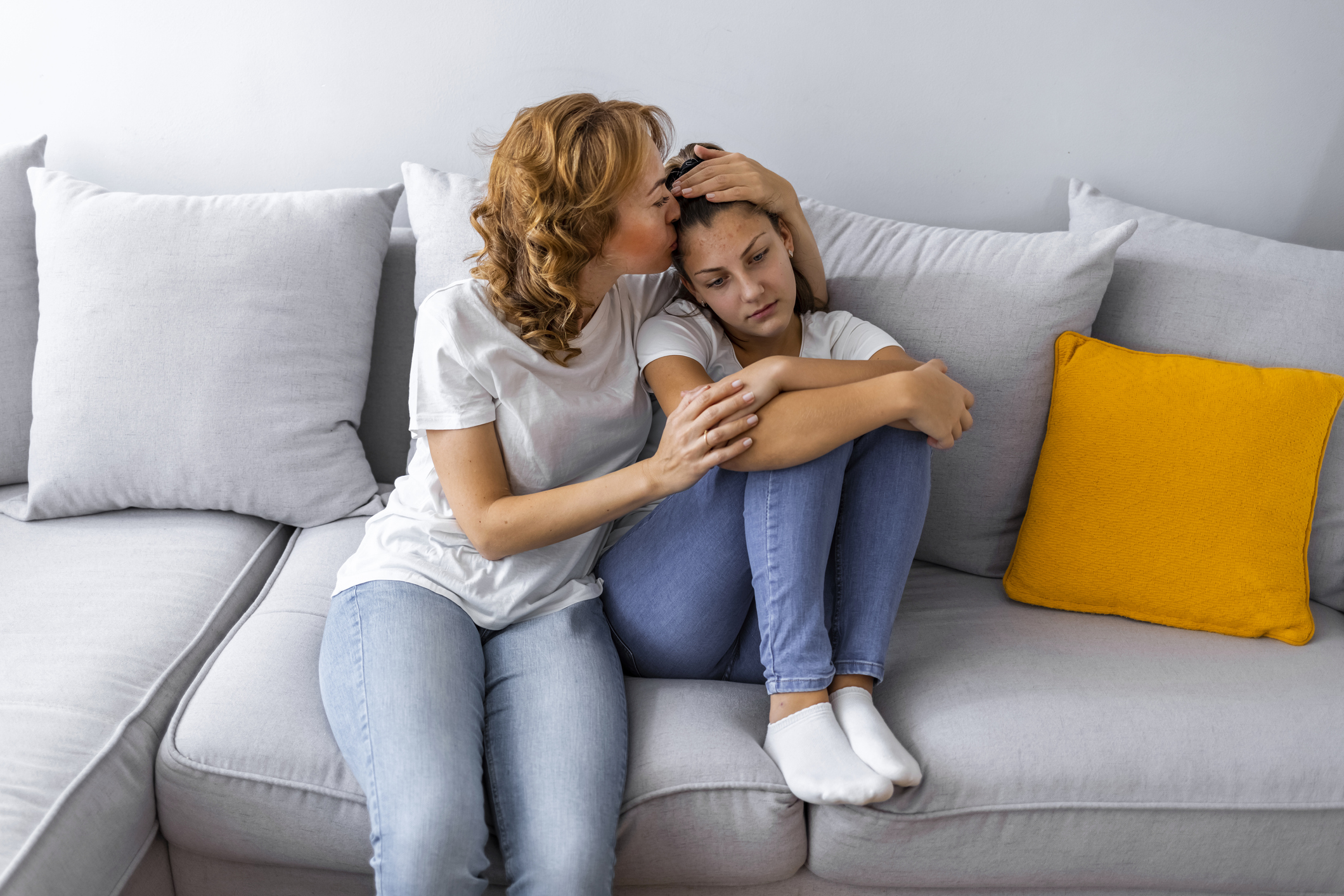 Caring mother calming and hugging upset little daughter