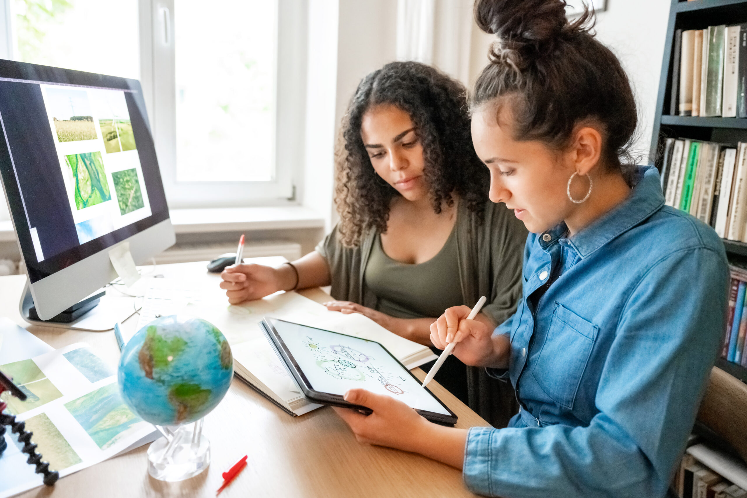 two young woman working together on concepts for climate protection