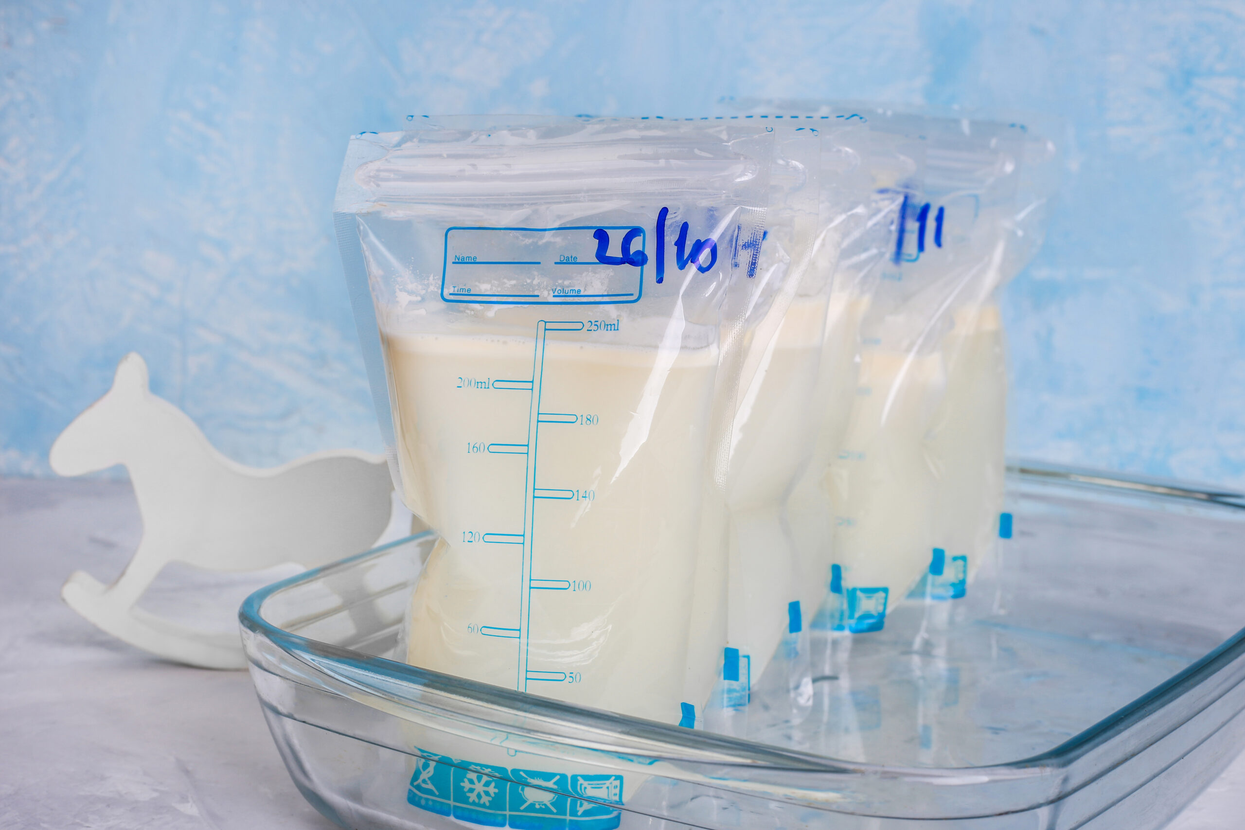 Bags with breast milk on blue background. Milk bank. Expressing breast milk. Breast-feeding. Freezing and storing milk. Donated.