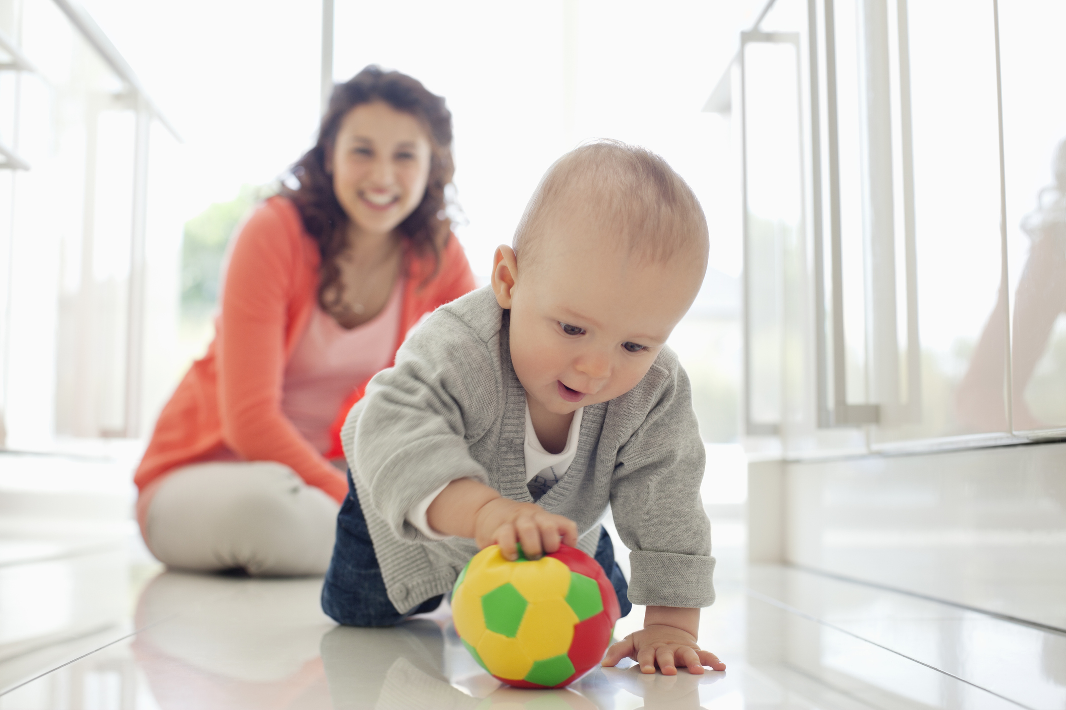 Mother watching baby playing with ball