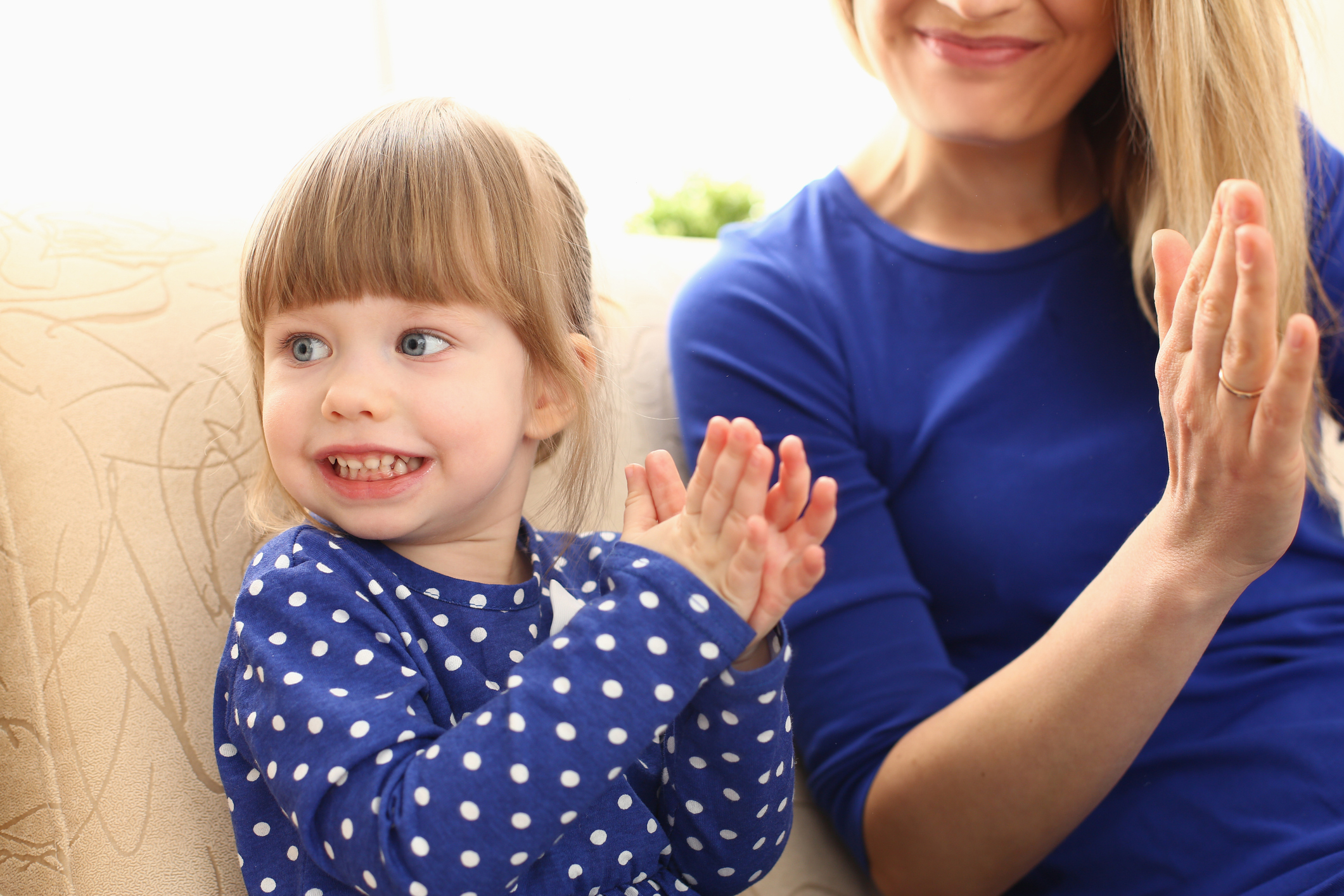 Cute little girl plays with mom and claps hands