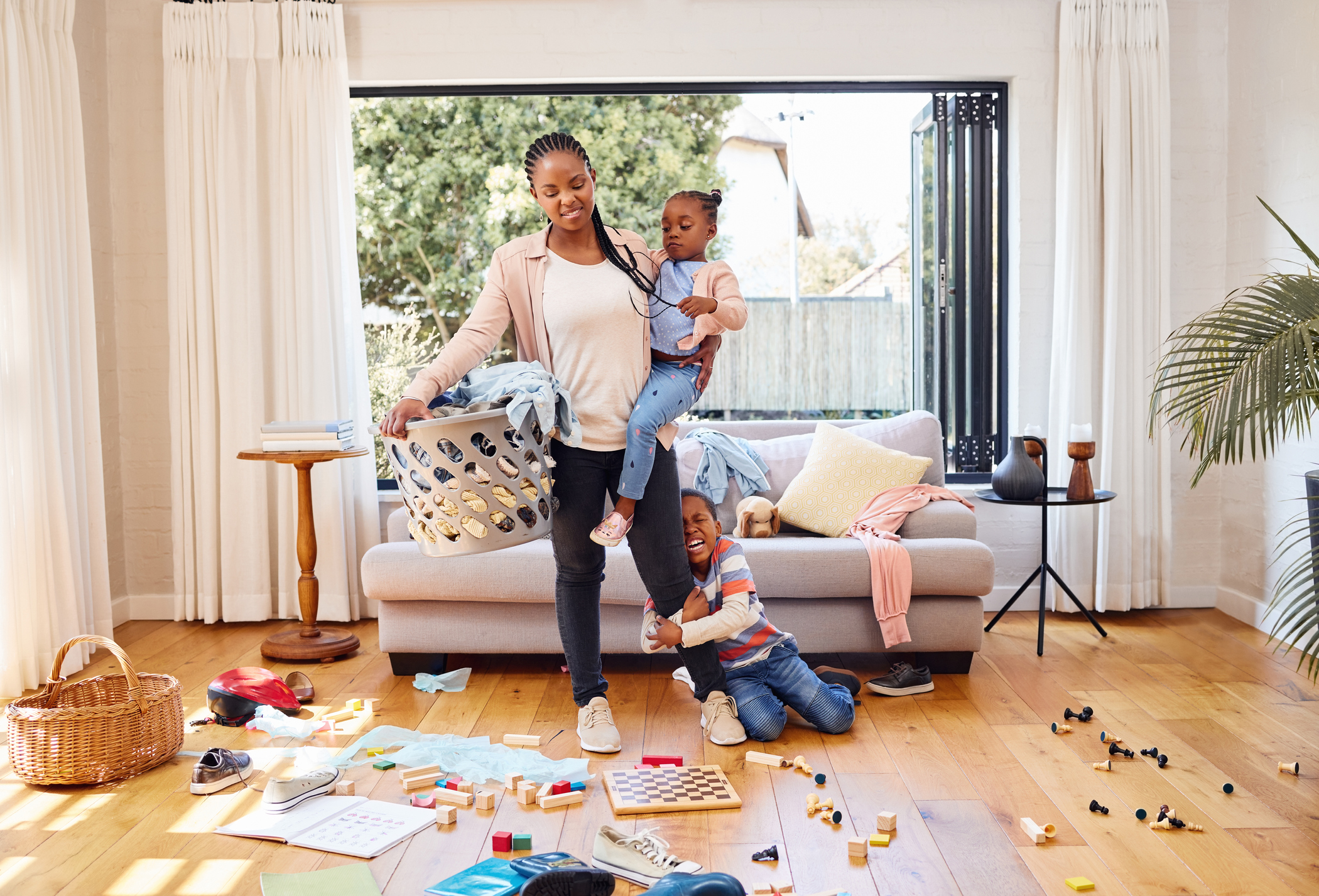 Shot of a little boy throwing a tantrum while holding his mother's leg at home