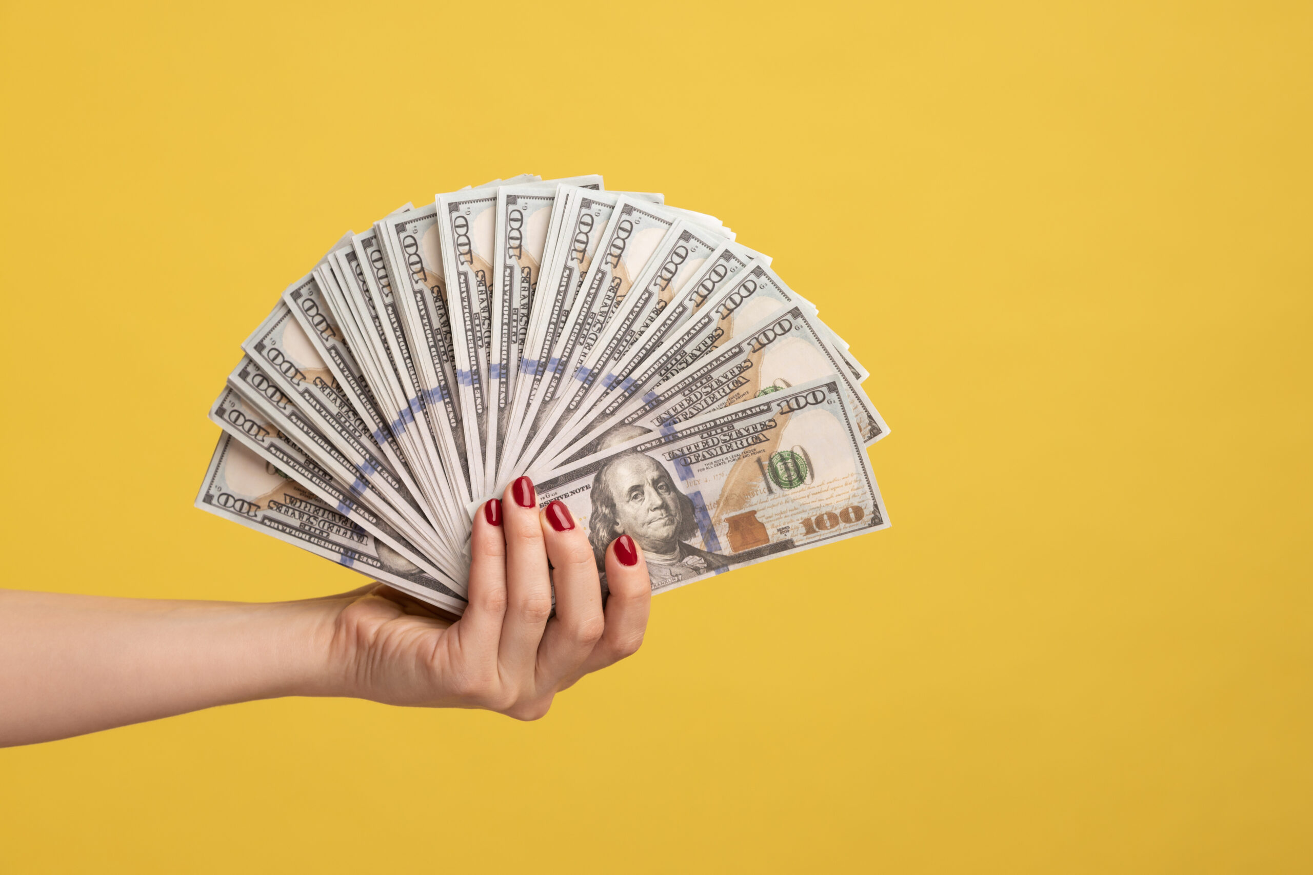 Side view closeup of woman hand showing fan of dollar banknotes, arm holding cash, lot of money.