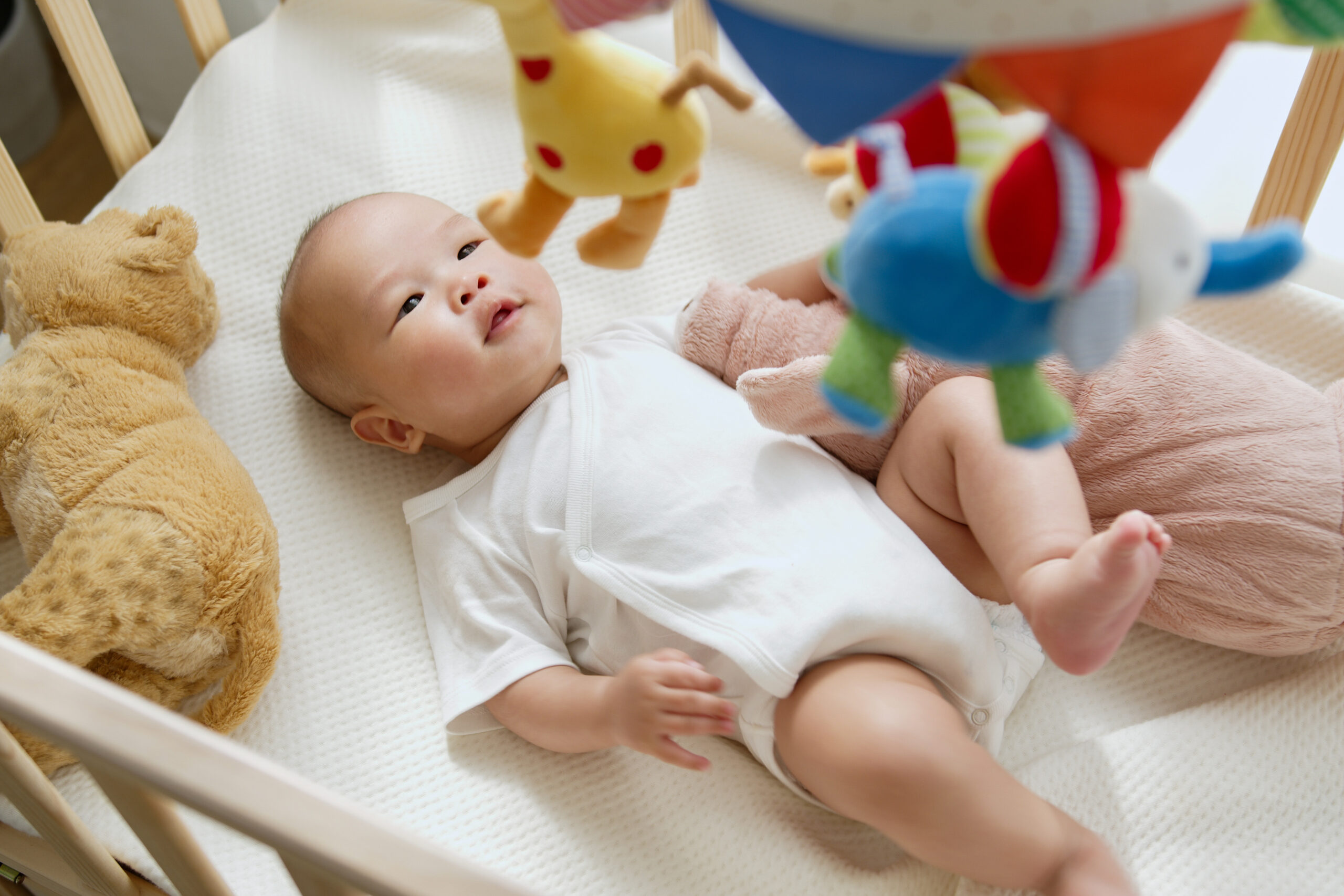 Asian newborn baby feeling joyful and happy with baby mobile crib